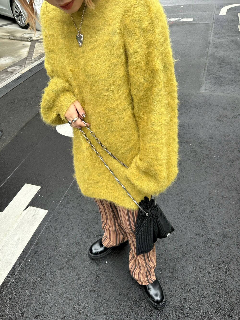 イエロー系のニット/セーター、ブラウン系のその他パンツ、ブラック系のバッグを着用したレディースの秋コーディネートの3枚目の写真