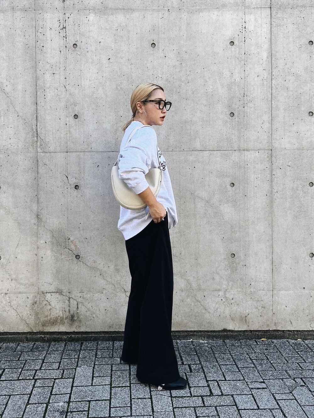 ブラック系のパンツ、グレー系のスウェット、ホワイト系のショルダーバッグを着用したレディースの秋コーディネートの3枚目の写真