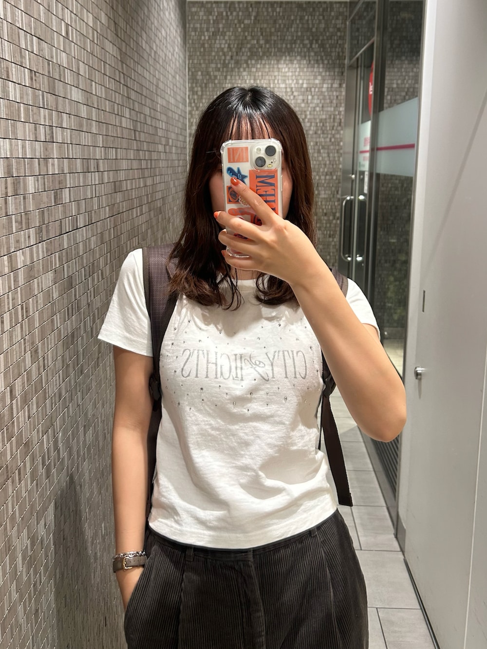 ベージュ系のスニーカー、ホワイト系のTシャツ/カットソー、ブラウン系のパンツを着用したレディースの秋コーディネートの2枚目の写真