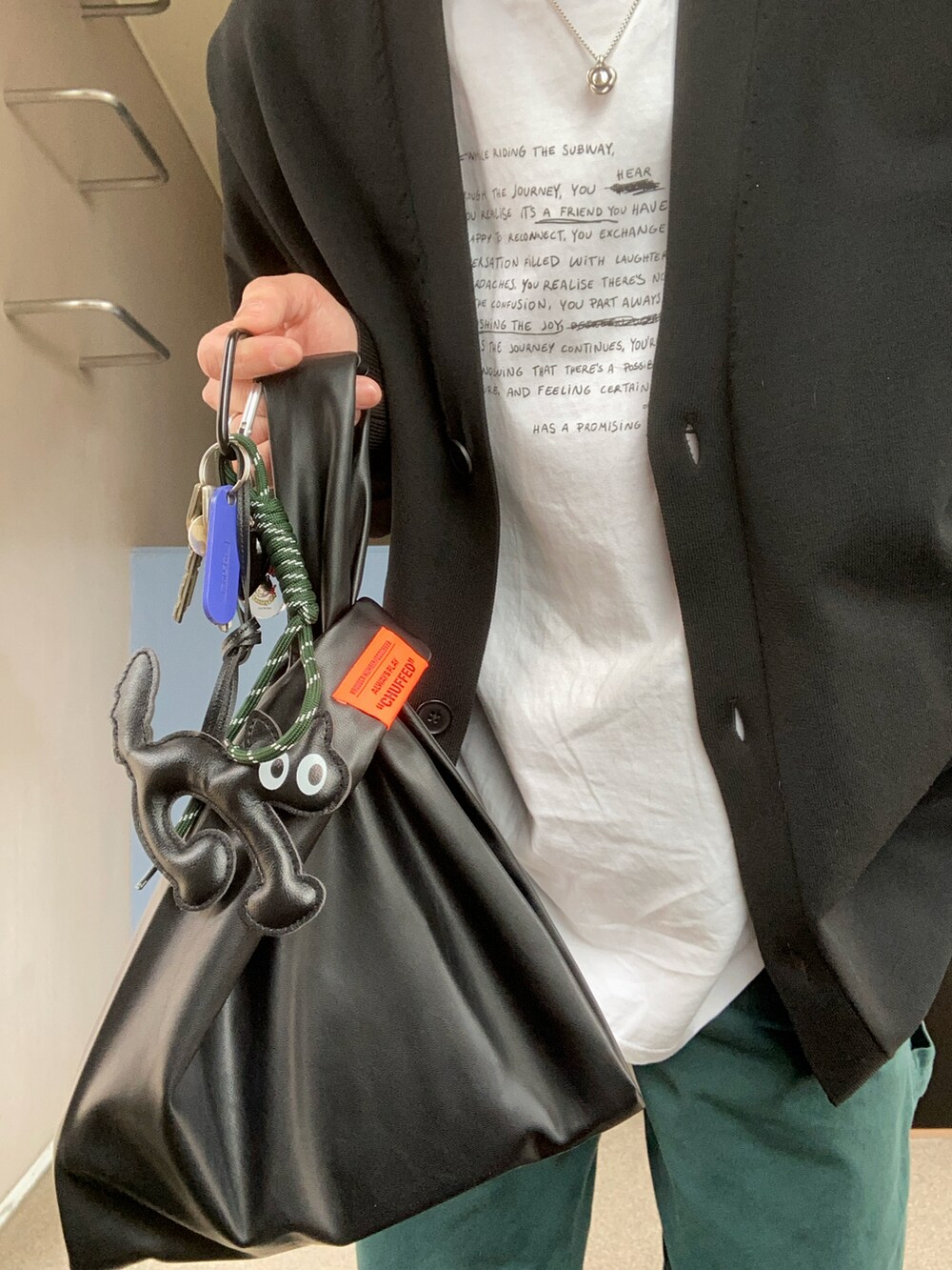 ホワイト系のTシャツ/カットソー、ブラック系のカーディガン/ボレロ、グリーン系のデニムパンツを着用したレディースの春コーディネートの2枚目の写真