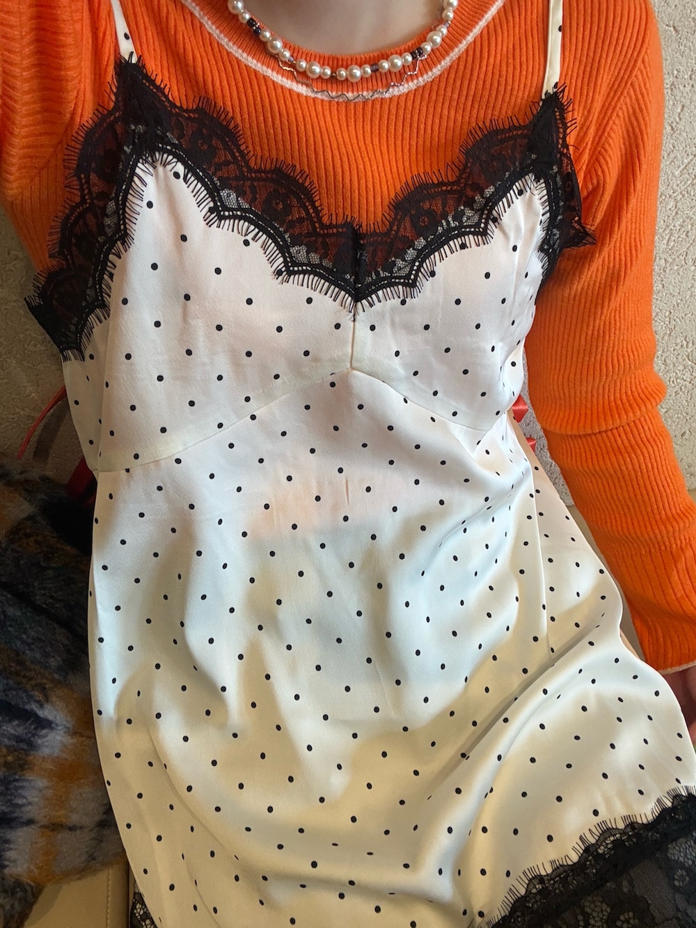 ホワイト系のキャミソール、オレンジ系のニット/セーター、グレー系のデニムパンツを着用したレディースの春コーディネートの4枚目の写真