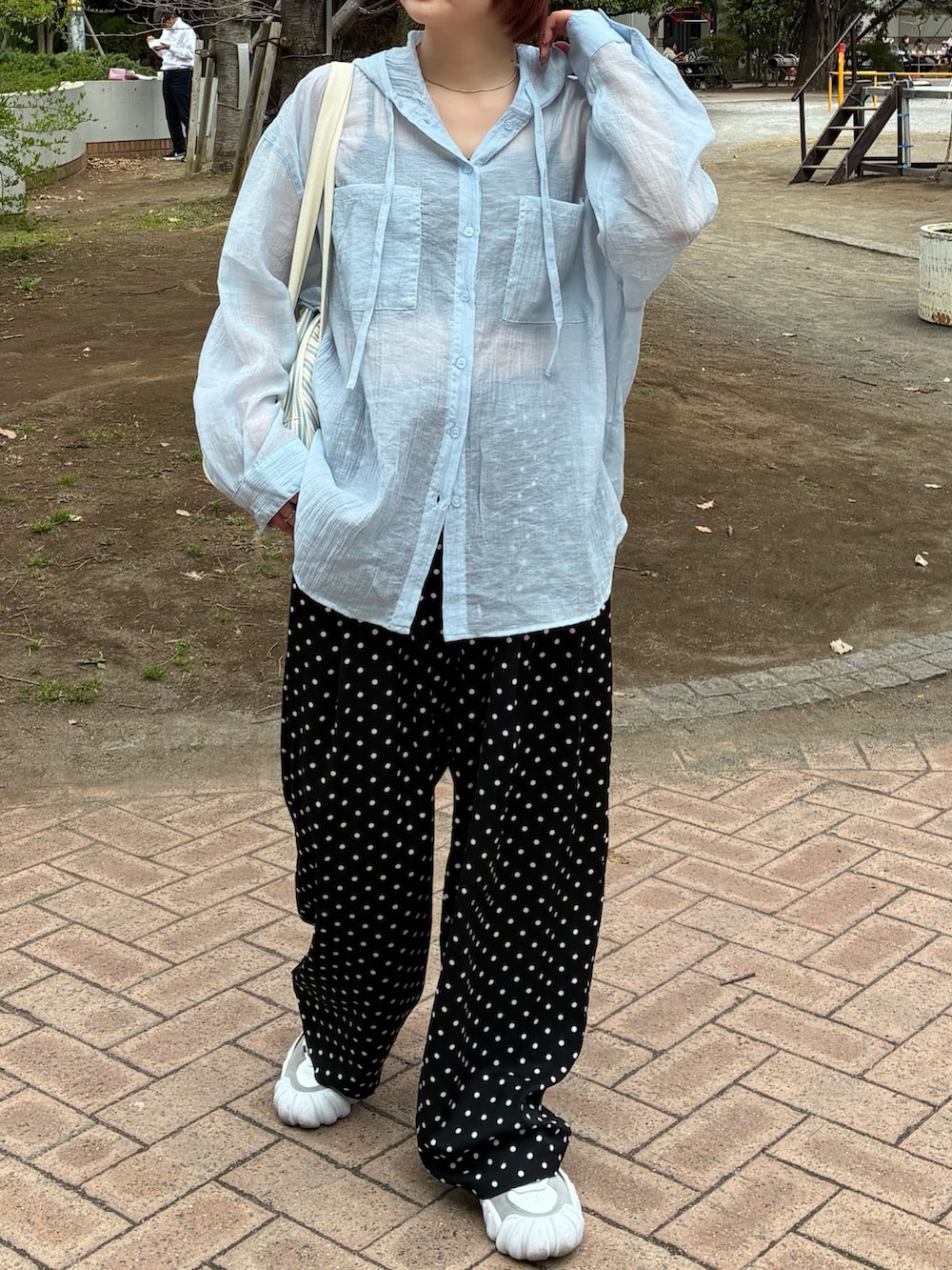 ブルー系のトップス、ホワイト系のボストンバッグ、ホワイト系のスニーカーを着用したレディースの春コーディネートの2枚目の写真