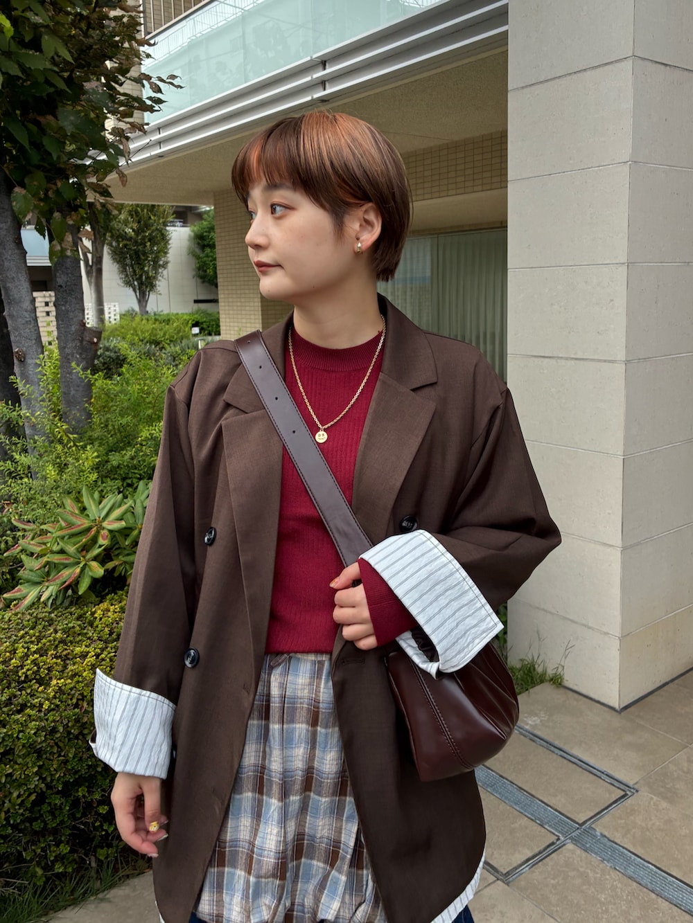 レッド系のニット/セーター、ブラウン系のスカート、ブルー系のデニムパンツを着用したレディースの秋コーディネートの2枚目の写真