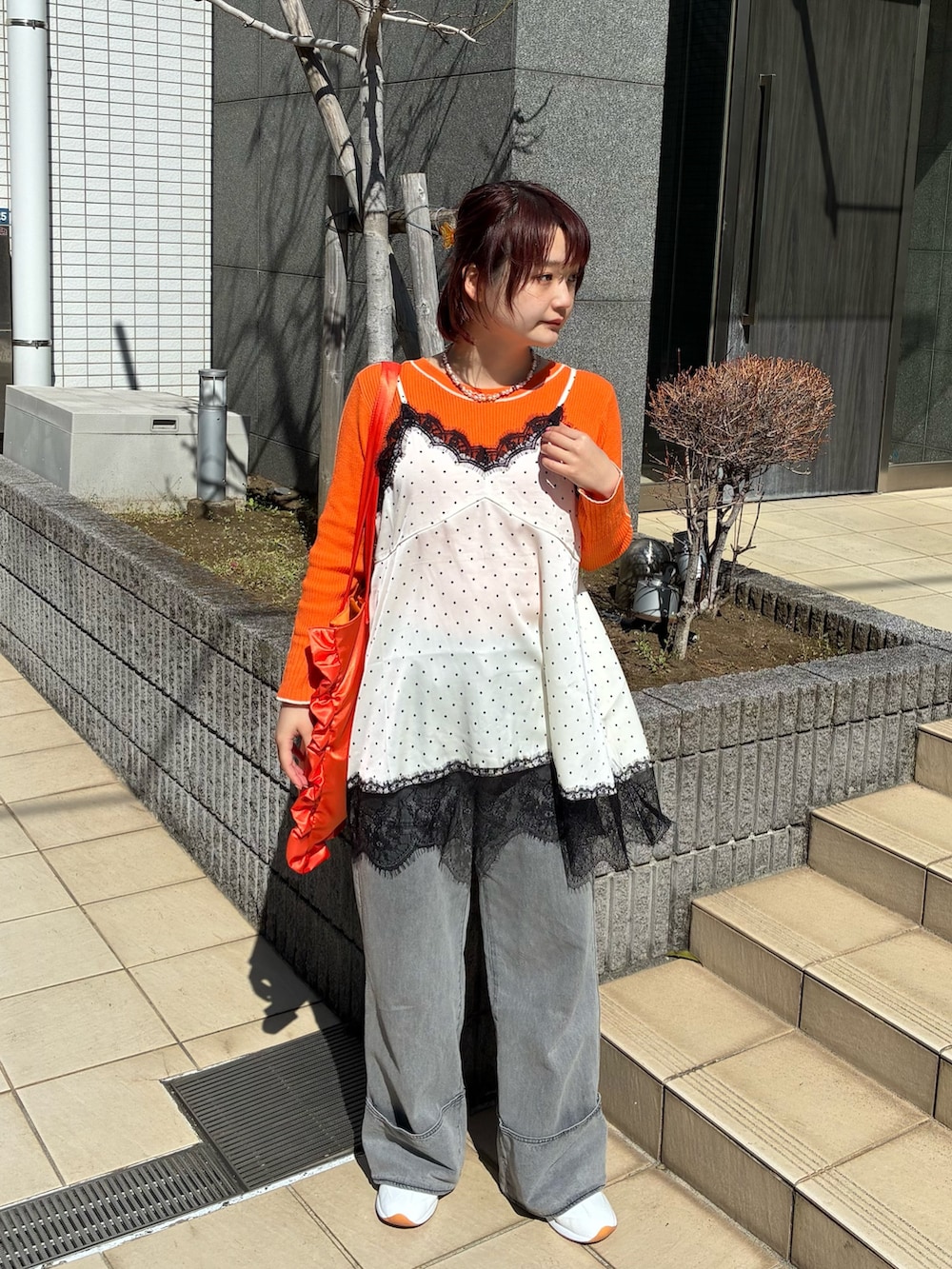 ホワイト系のキャミソール、オレンジ系のニット/セーター、グレー系のデニムパンツを着用したレディースの春コーディネートの2枚目の写真