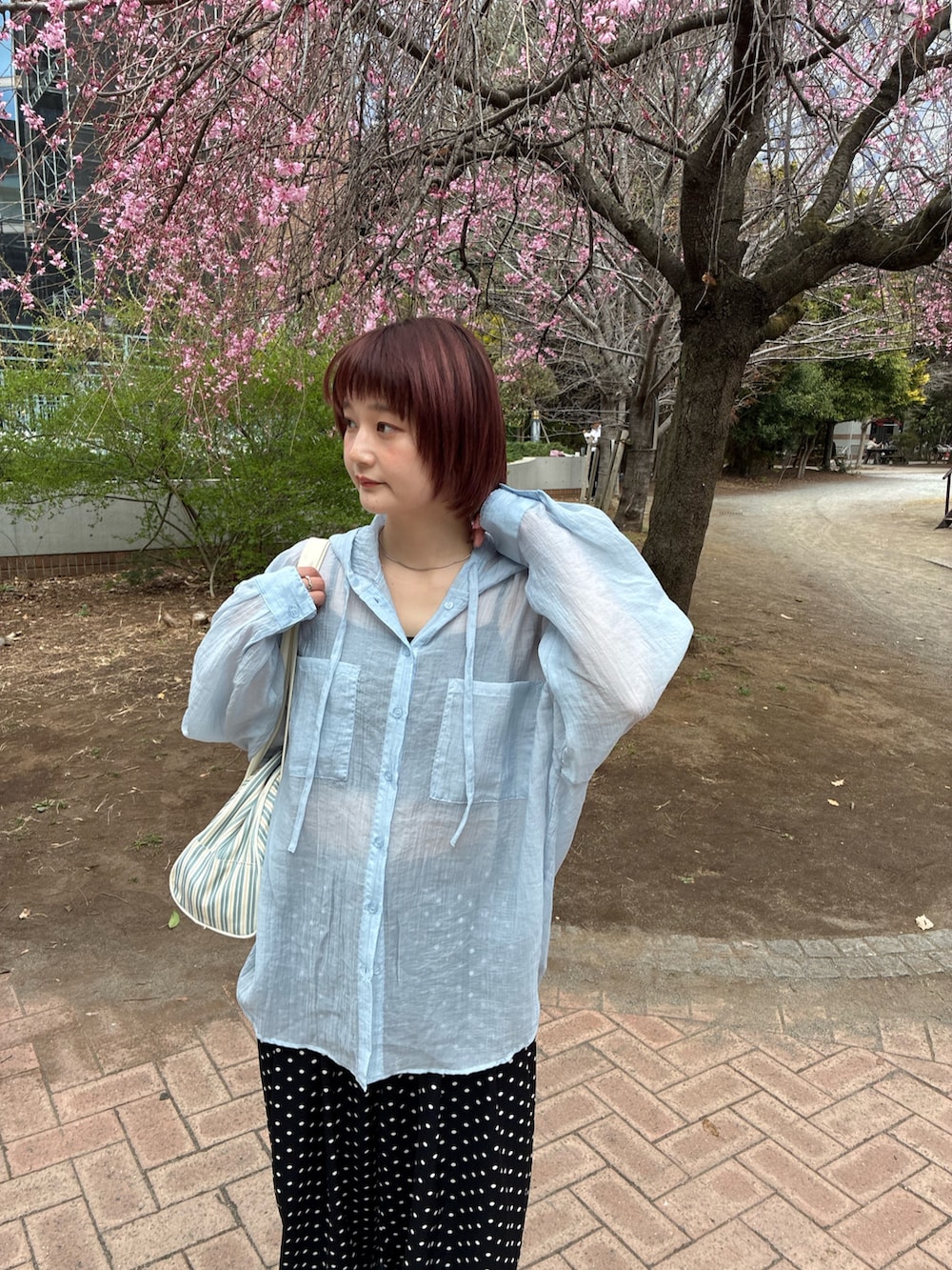 ブルー系のトップス、ホワイト系のボストンバッグ、ホワイト系のスニーカーを着用したレディースの春コーディネートの4枚目の写真