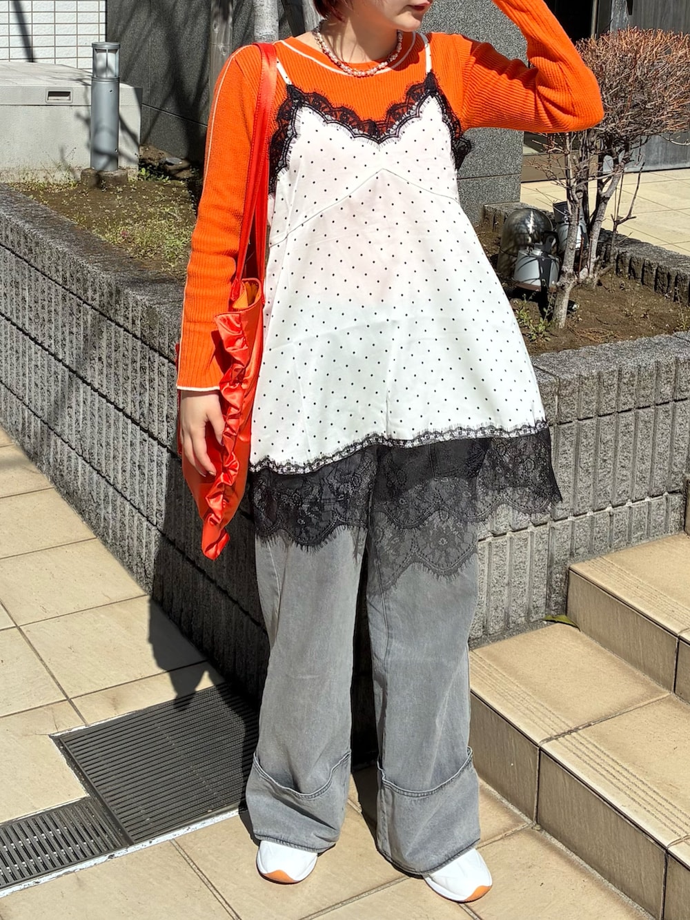 ホワイト系のキャミソール、オレンジ系のニット/セーター、グレー系のデニムパンツを着用したレディースの春コーディネートの5枚目の写真