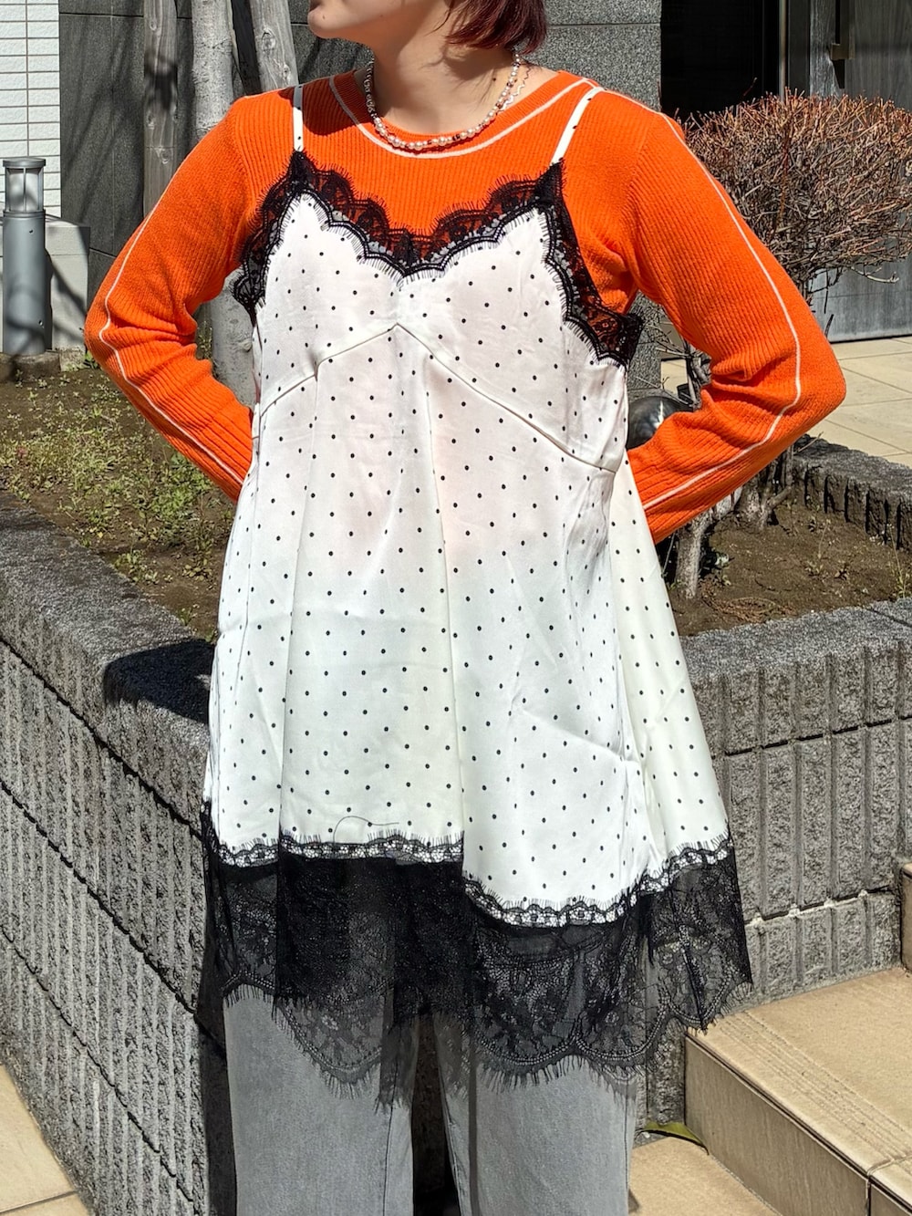 ホワイト系のキャミソール、オレンジ系のニット/セーター、グレー系のデニムパンツを着用したレディースの春コーディネートの3枚目の写真