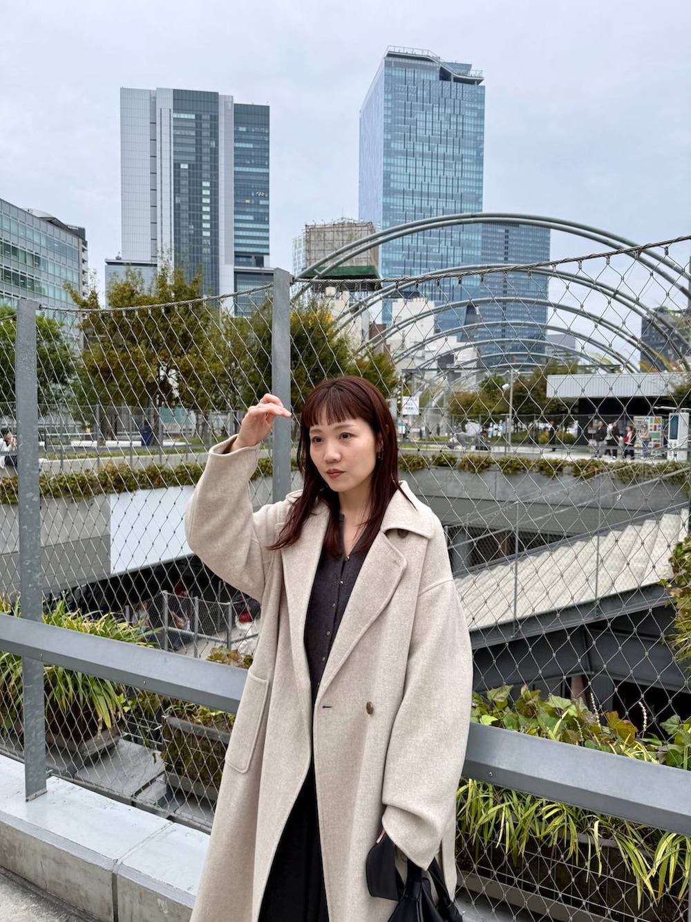 ベージュ系のステンカラーコート、ブラック系のブーツ、グレー系のカーディガン/ボレロを着用したレディースの秋コーディネートの6枚目の写真