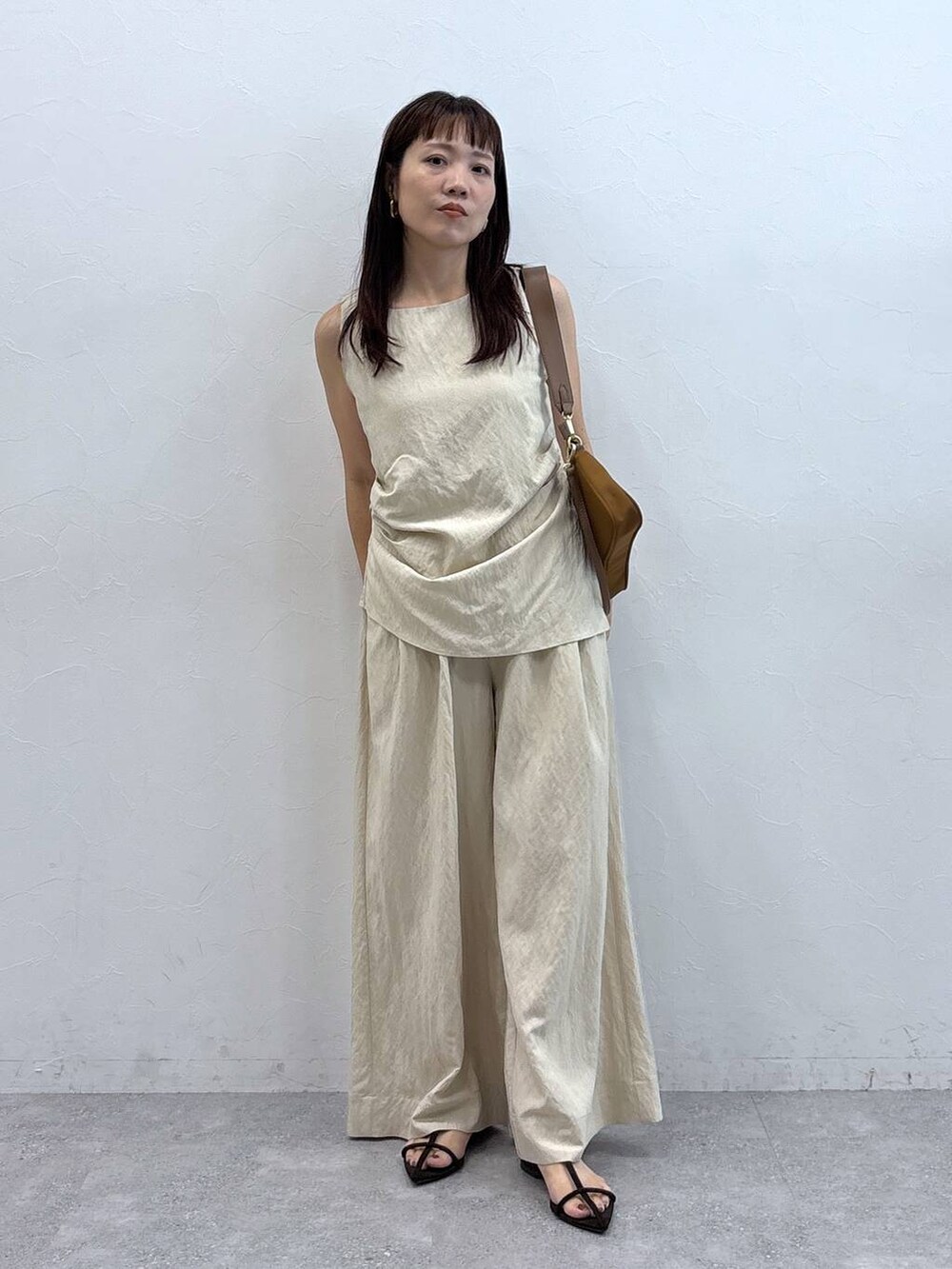 イエロー系のショルダーバッグ、ベージュ系のパンツドレスを着用したレディースの夏コーディネートの3枚目の写真