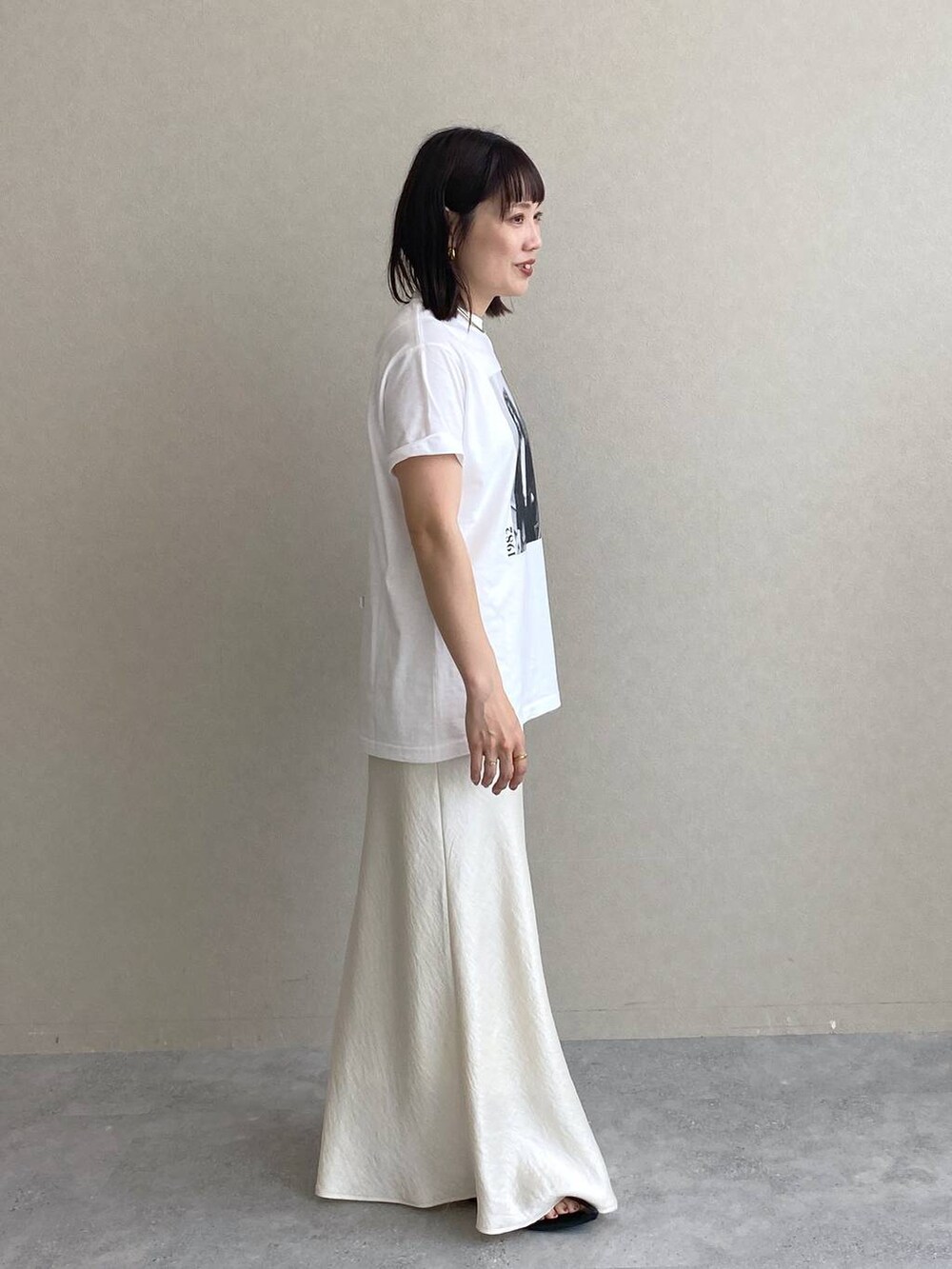 ホワイト系のTシャツ/カットソー、ホワイト系のスカート、ブラック系のサンダルを着用したレディースの春コーディネートの2枚目の写真