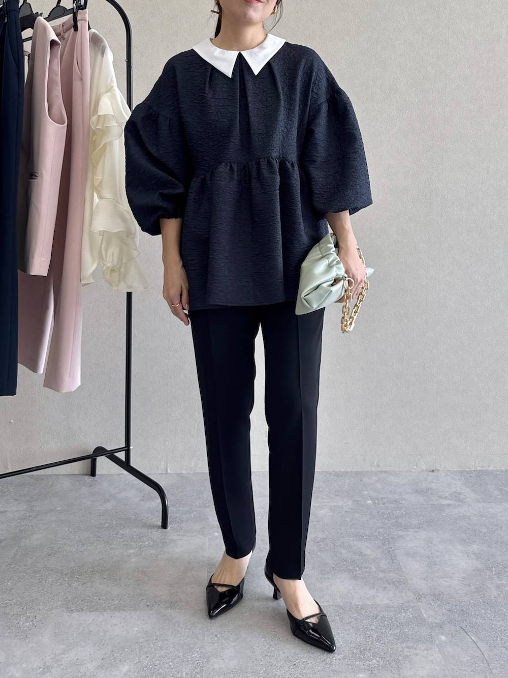 ブラック系のパンプス、グリーン系のショルダーバッグ、ブルー系のパンツドレスを着用したレディースの冬コーディネートの8枚目の写真