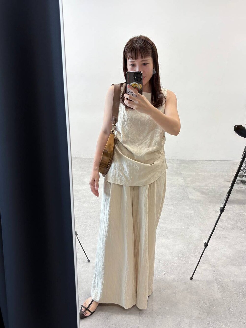 イエロー系のショルダーバッグ、ベージュ系のパンツドレスを着用したレディースの夏コーディネートの4枚目の写真