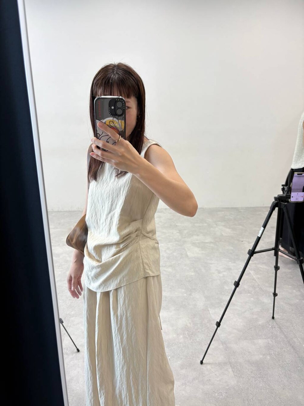 イエロー系のショルダーバッグ、ベージュ系のパンツドレスを着用したレディースの夏コーディネートの5枚目の写真