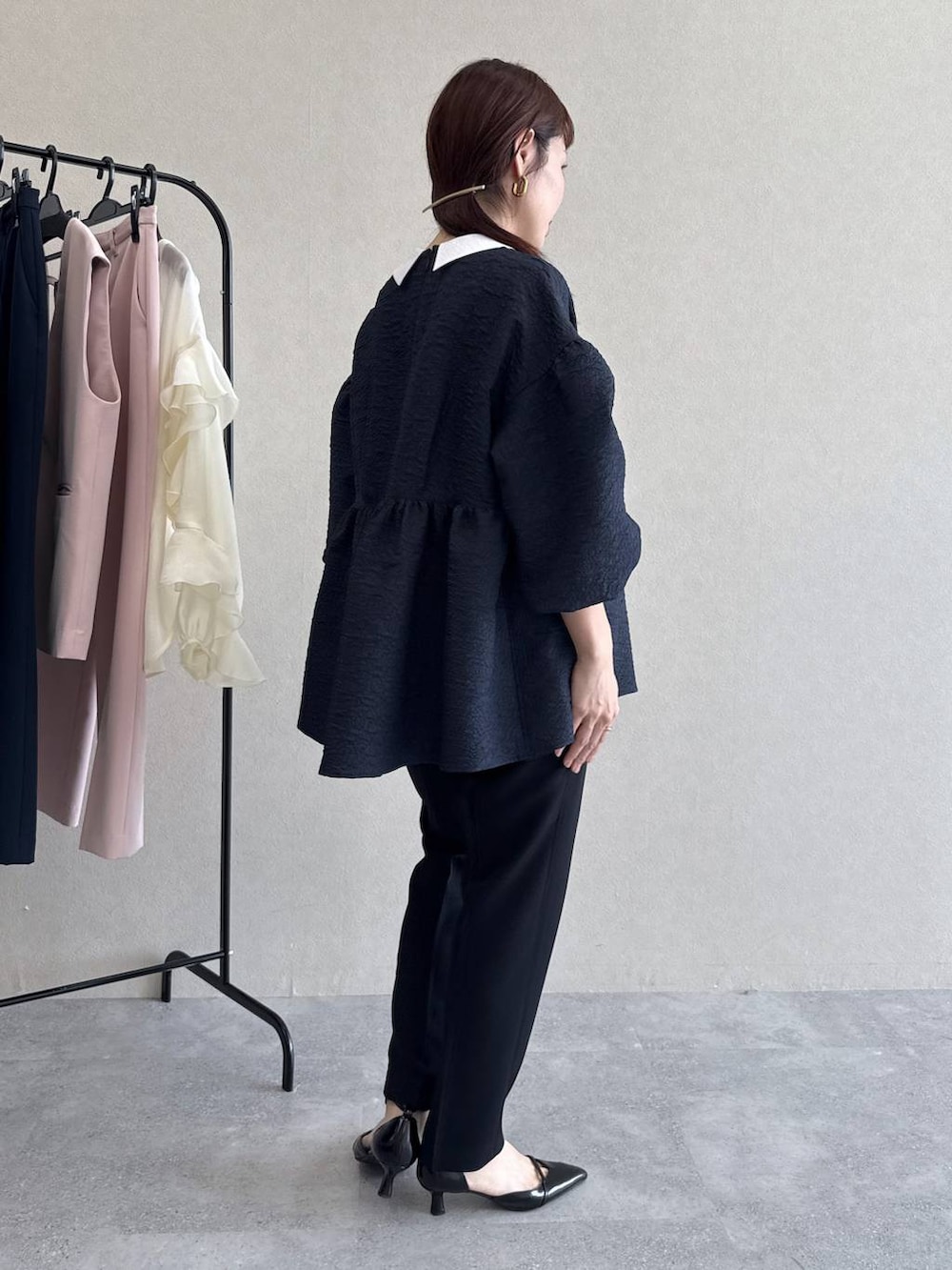 ブラック系のパンプス、グリーン系のショルダーバッグ、ブルー系のパンツドレスを着用したレディースの冬コーディネートの3枚目の写真