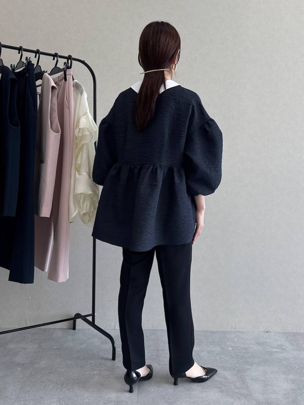 ブラック系のパンプス、グリーン系のショルダーバッグ、ブルー系のパンツドレスを着用したレディースの冬コーディネートの6枚目の写真