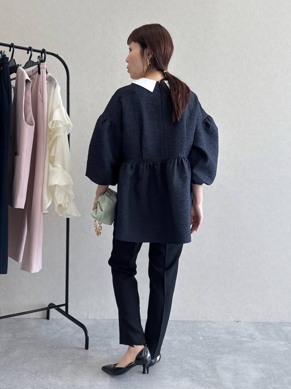 ブラック系のパンプス、グリーン系のショルダーバッグ、ブルー系のパンツドレスを着用したレディースの冬コーディネートの5枚目の写真