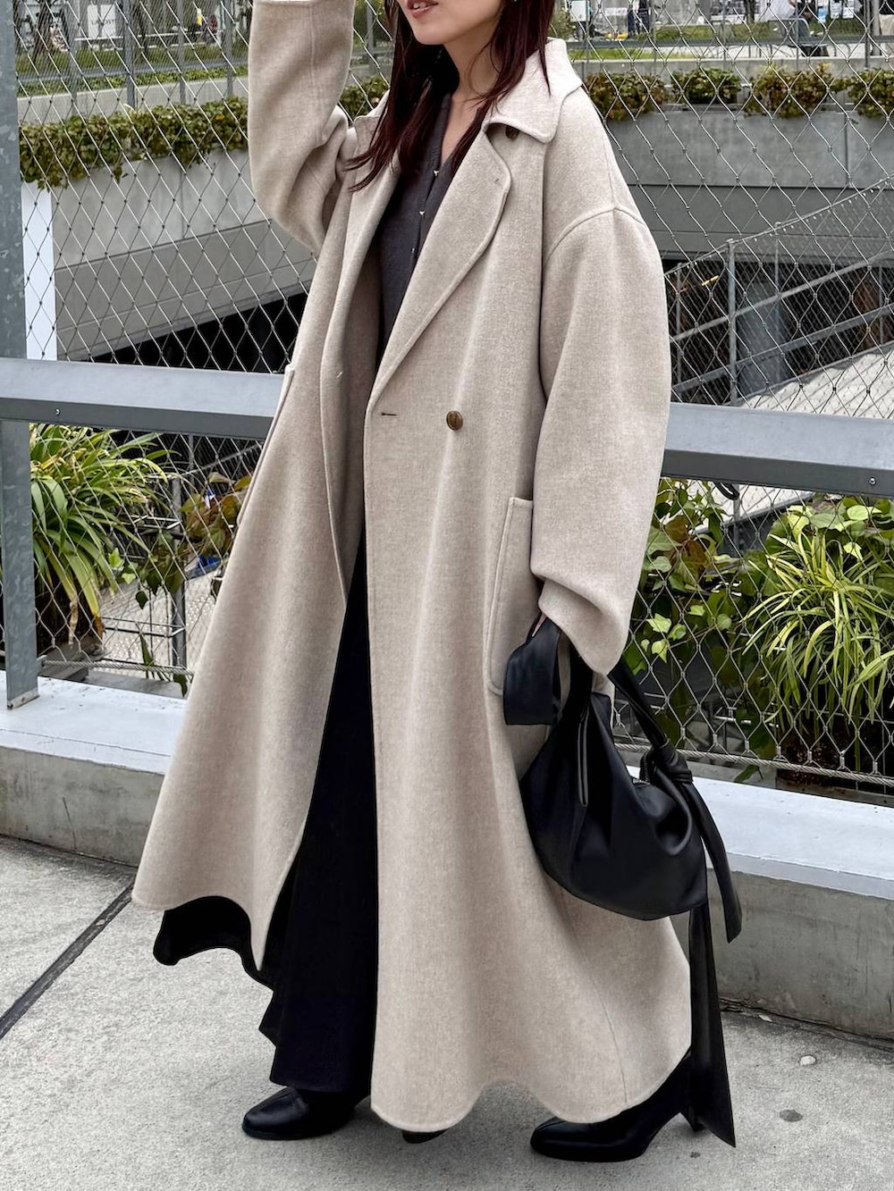 ベージュ系のステンカラーコート、ブラック系のブーツ、グレー系のカーディガン/ボレロを着用したレディースの秋コーディネートの4枚目の写真