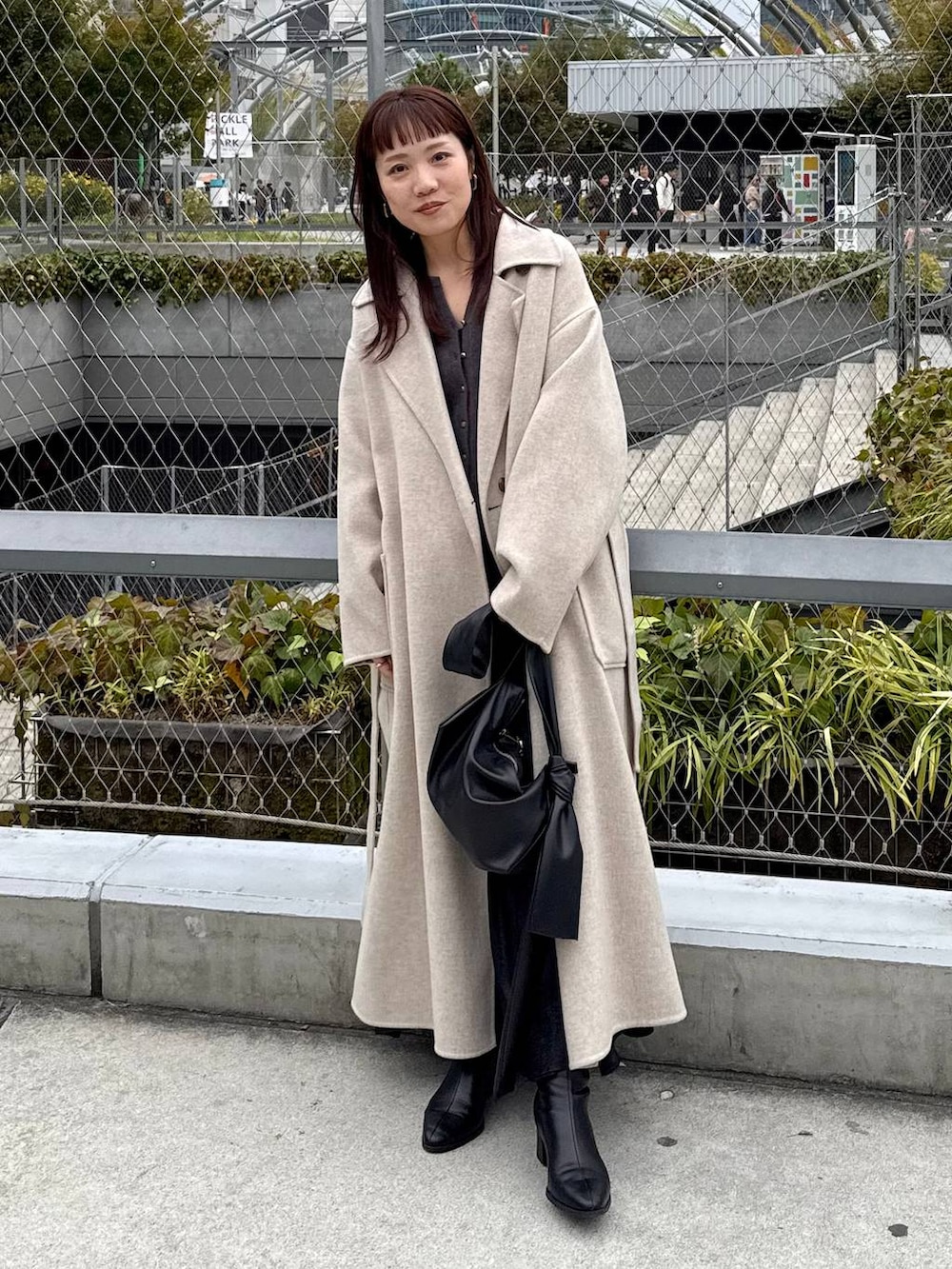 ベージュ系のステンカラーコート、ブラック系のブーツ、グレー系のカーディガン/ボレロを着用したレディースの秋コーディネートの5枚目の写真