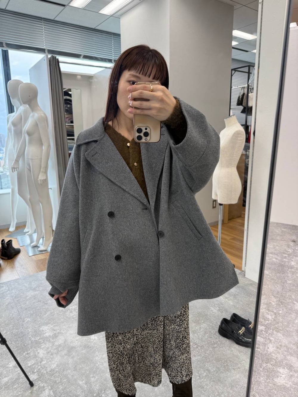 グレー系のその他アウター、ベージュ系のスカート、ブラウン系のブーツを着用したレディースの秋コーディネートの3枚目の写真