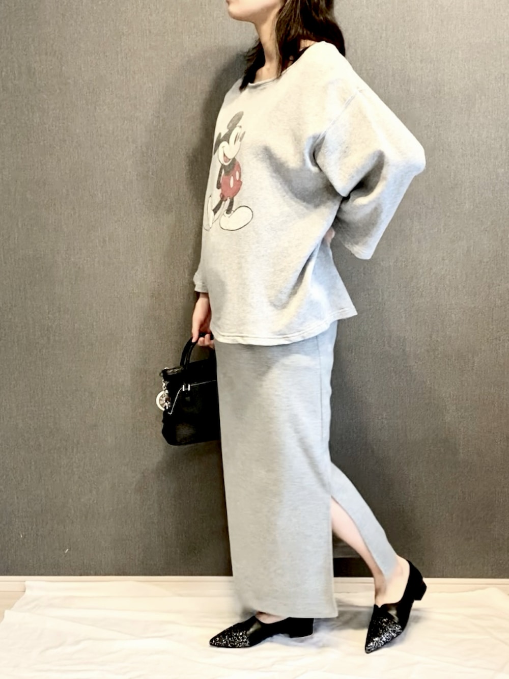 グレー系のスウェット、グレー系のスカート、ブラック系のショルダーバッグを着用したレディースの春コーディネートの2枚目の写真