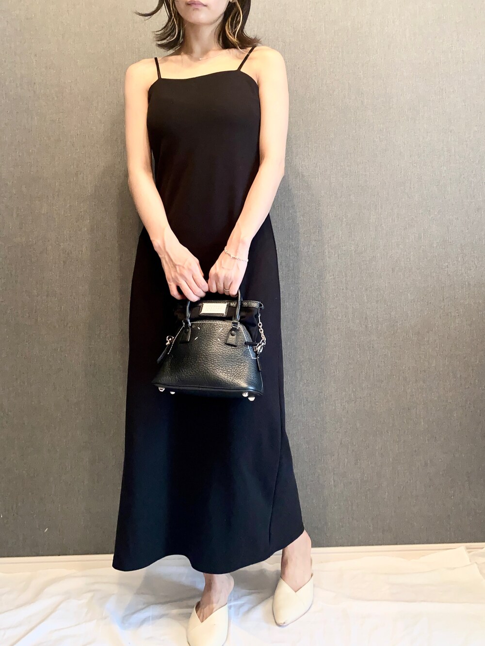 ブラック系のショルダーバッグ、ブラック系のワンピース、ホワイト系のサンダルを着用したレディースの夏コーディネートの2枚目の写真