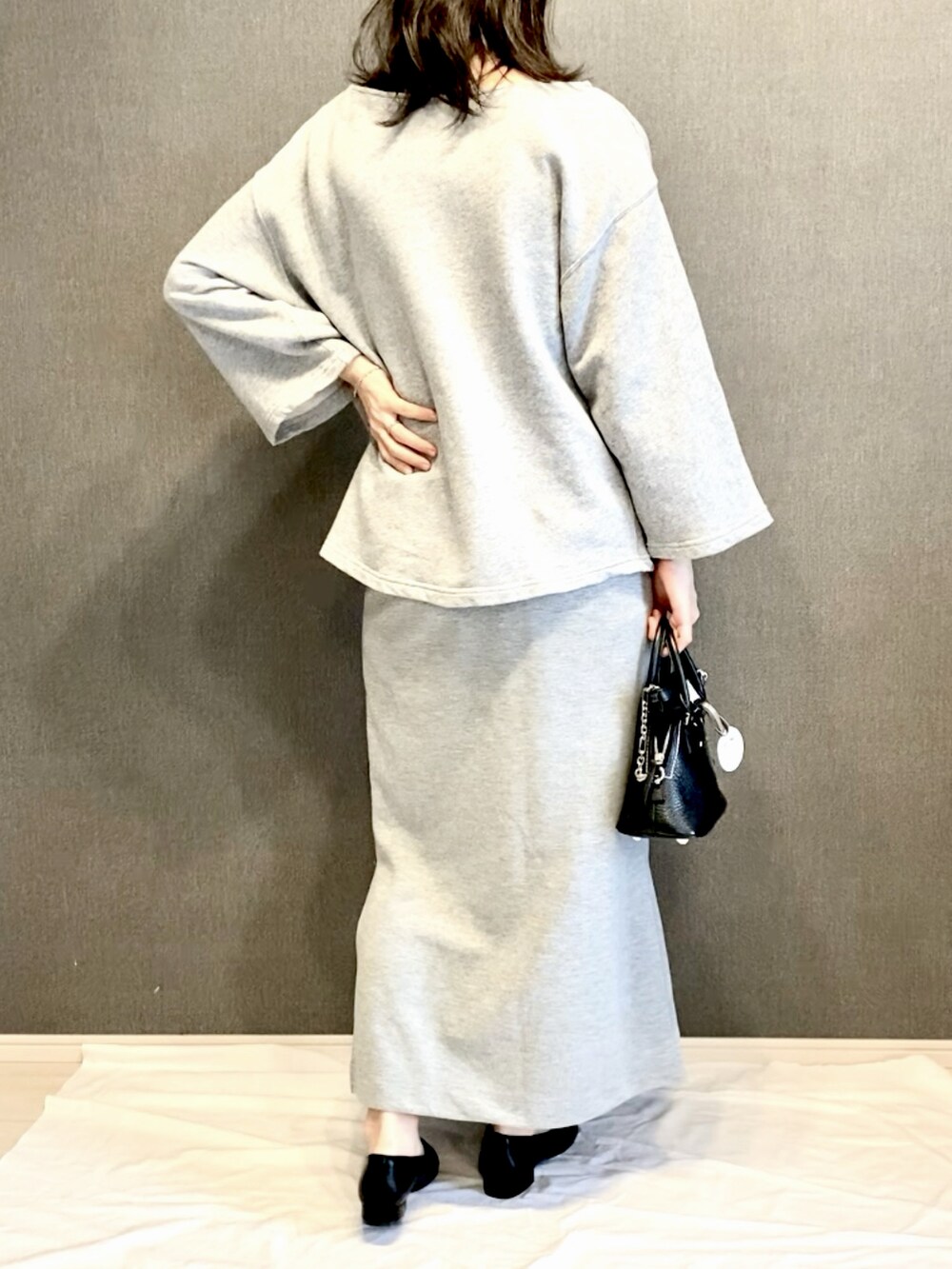 グレー系のスウェット、グレー系のスカート、ブラック系のショルダーバッグを着用したレディースの春コーディネートの3枚目の写真