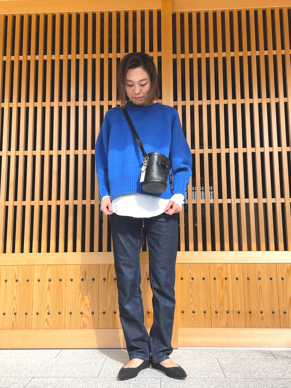 ブルー系のニット/セーター、ブラック系のショルダーバッグ、ブルー系のデニムパンツを着用したレディースの冬コーディネートの2枚目の写真