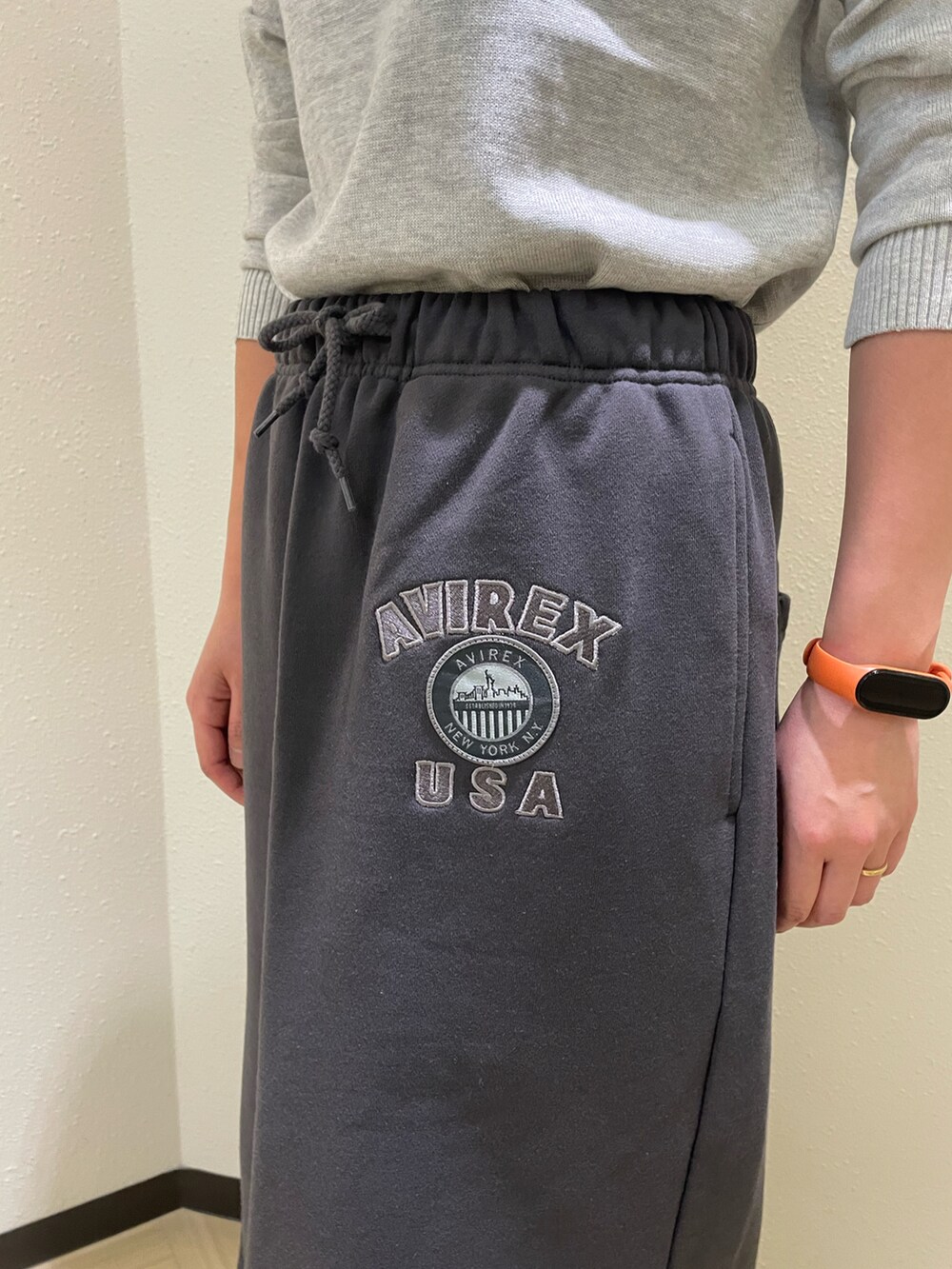 グレー系のニット/セーター、グレー系のスカート、グリーン系のキャップを着用したレディースの秋コーディネートの4枚目の写真