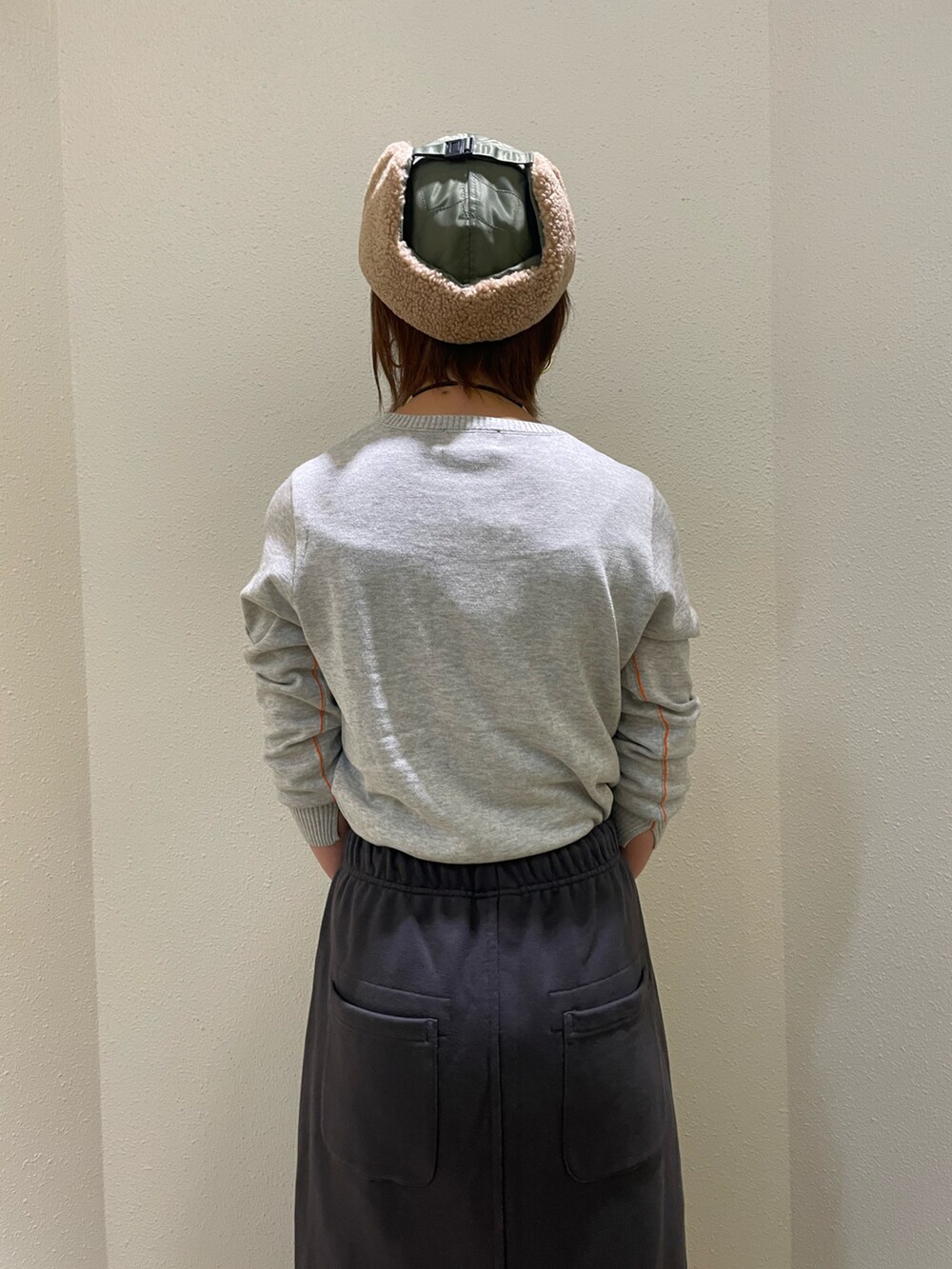 グレー系のニット/セーター、グレー系のスカート、グリーン系のキャップを着用したレディースの秋コーディネートの3枚目の写真