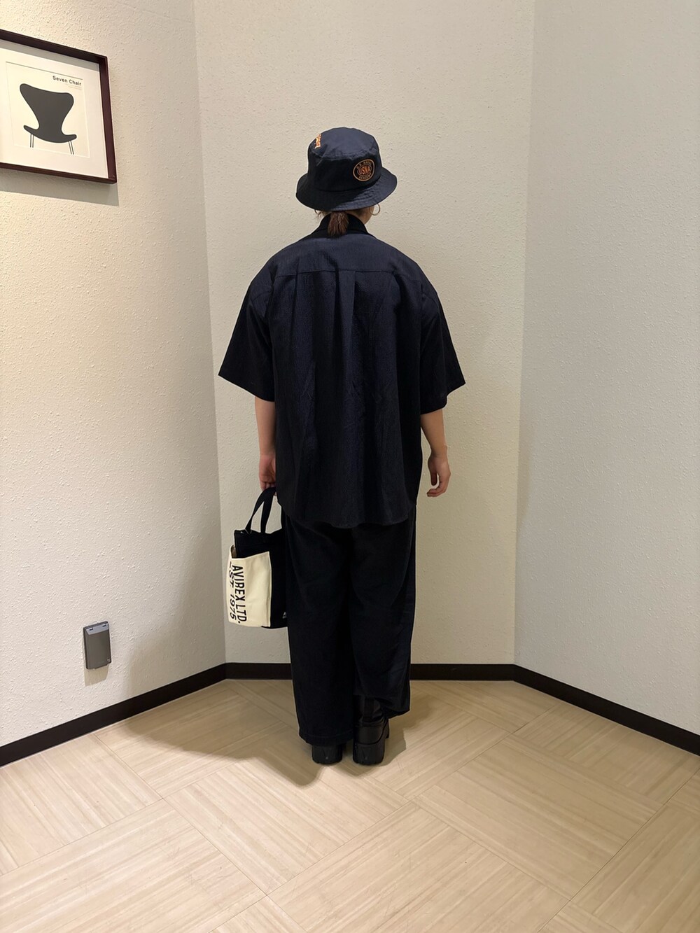 ブラック系のトートバッグ、ブラック系のシャツ/ブラウス、ブラック系のハットを着用したレディースの夏コーディネートの2枚目の写真