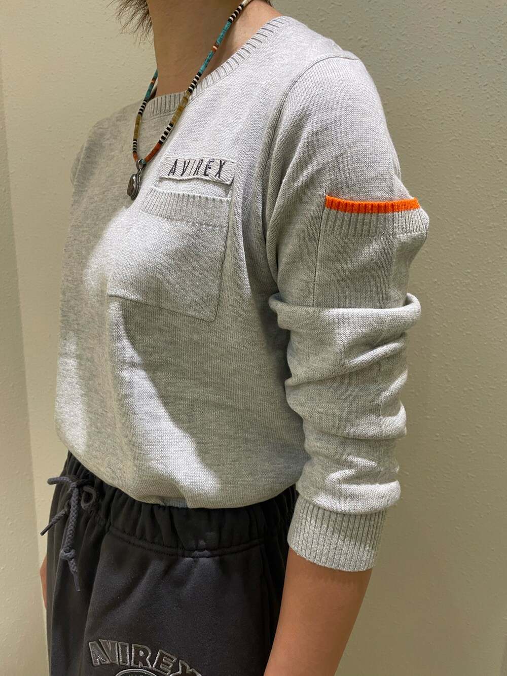 グレー系のニット/セーター、グレー系のスカート、グリーン系のキャップを着用したレディースの秋コーディネートの5枚目の写真