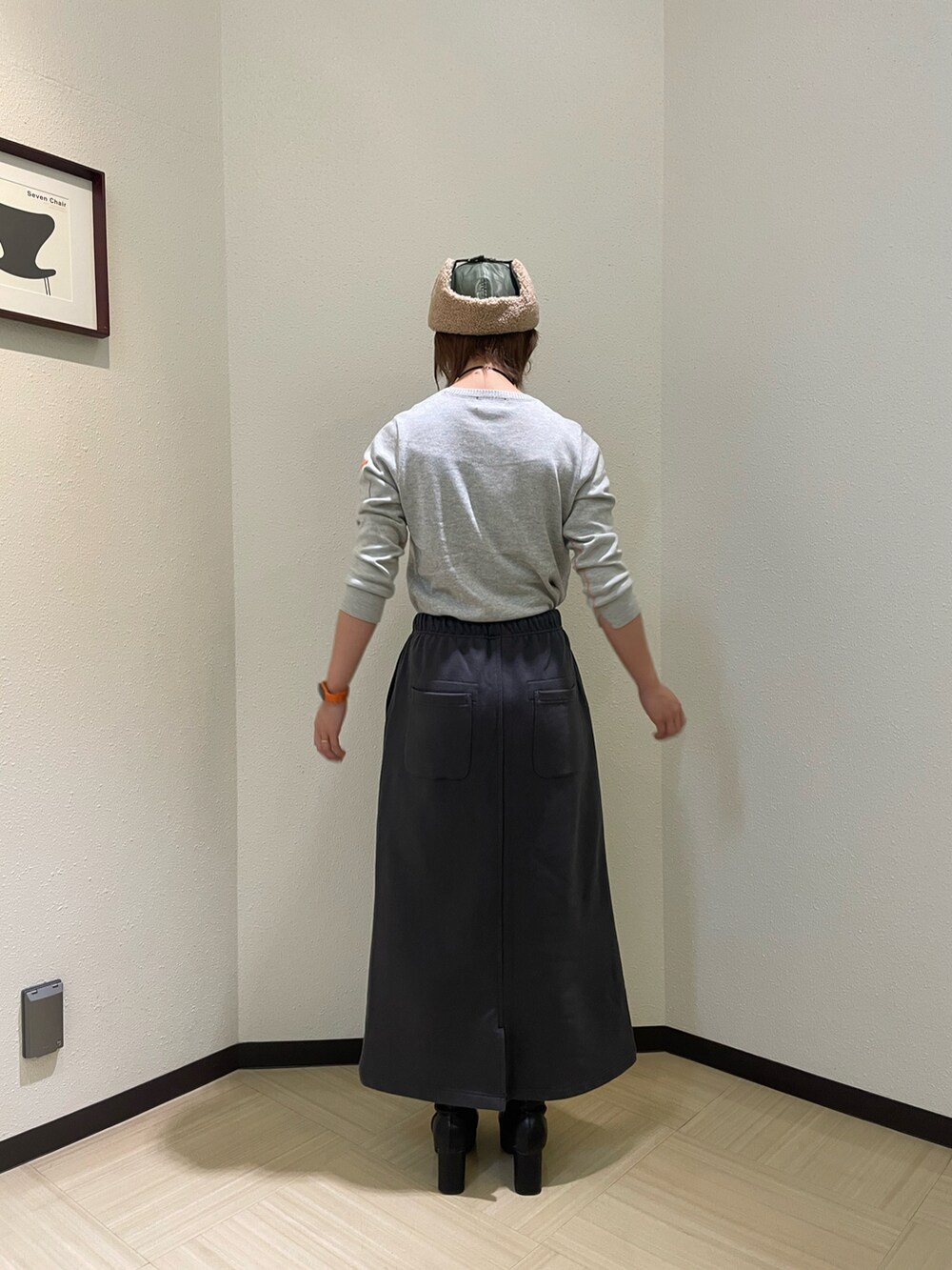 グレー系のニット/セーター、グレー系のスカート、グリーン系のキャップを着用したレディースの秋コーディネートの2枚目の写真