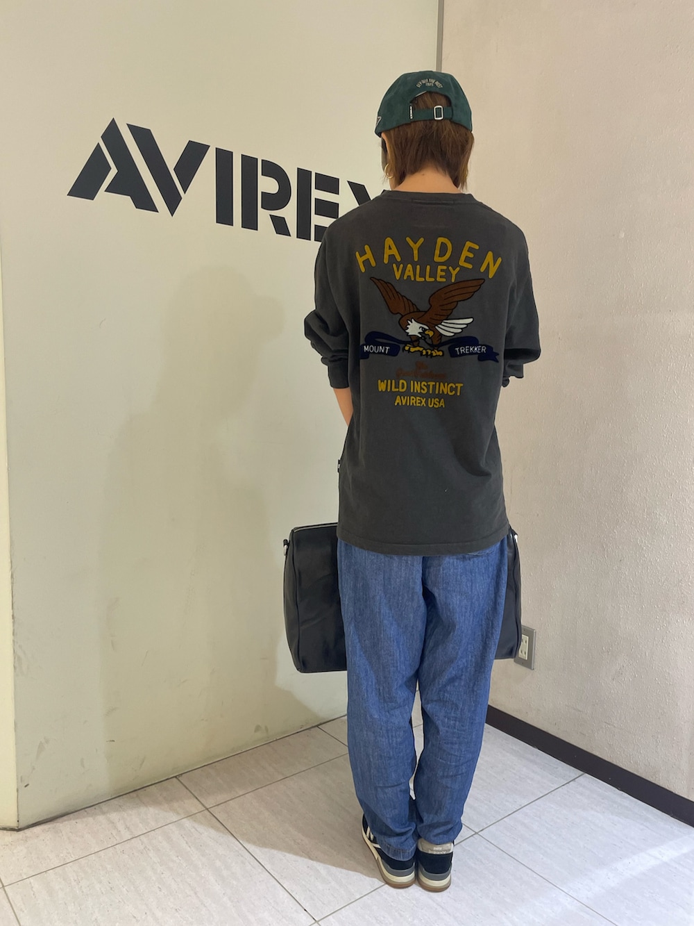 ブラック系のTシャツ/カットソー、ブラック系のボストンバッグ、グリーン系のキャップを着用したレディースの秋コーディネートの2枚目の写真