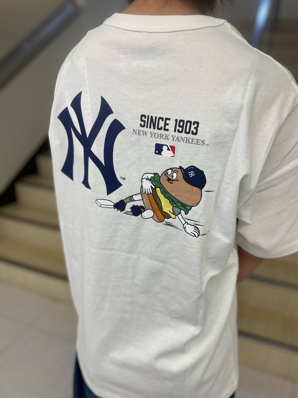 ホワイト系のTシャツ/カットソー、ブラック系のショルダーバッグ、ブルー系のキャップを着用したレディースの夏コーディネートの4枚目の写真