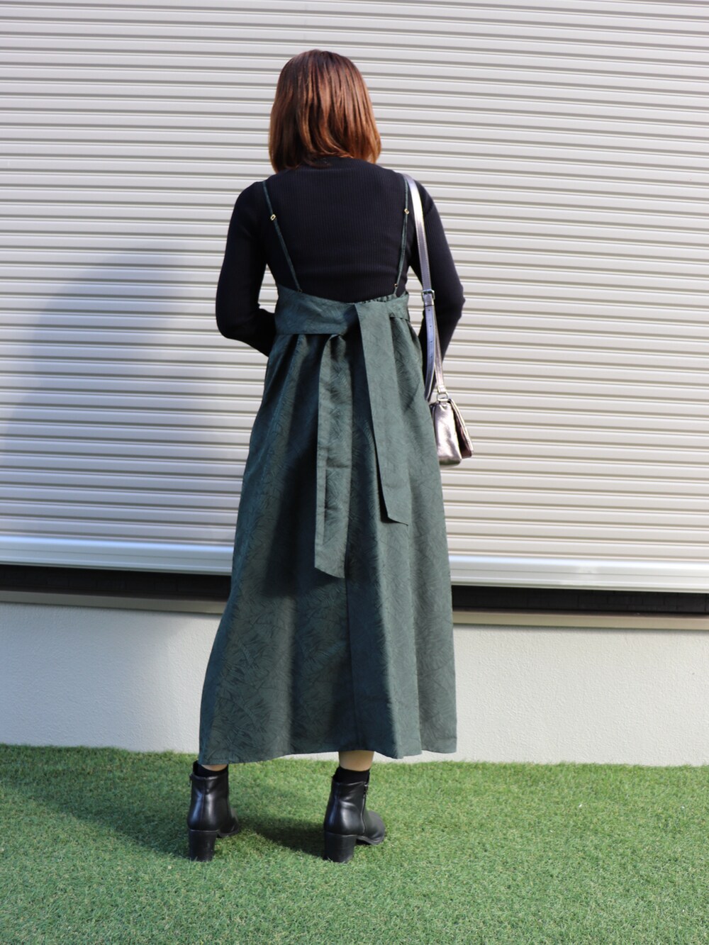 グリーン系のワンピース/ドレス、ブラック系のニット/セーター、ブラック系のシューズを着用したレディースの秋コーディネートの2枚目の写真