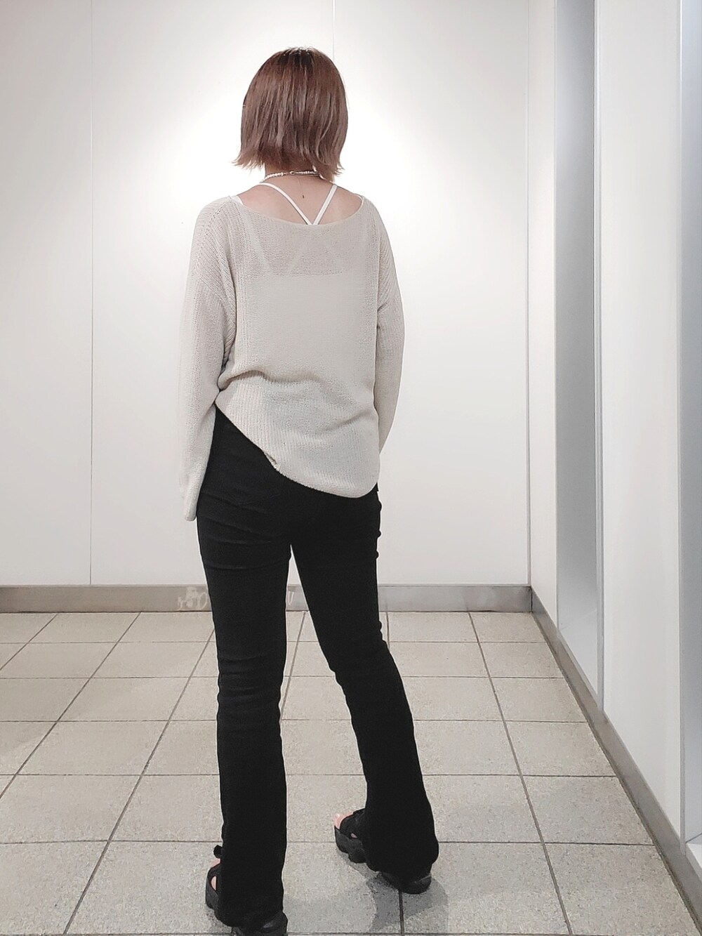 ホワイト系のニット/セーター、ブラック系のパンツ、ブラック系のサンダルを着用したレディースの夏コーディネートの2枚目の写真