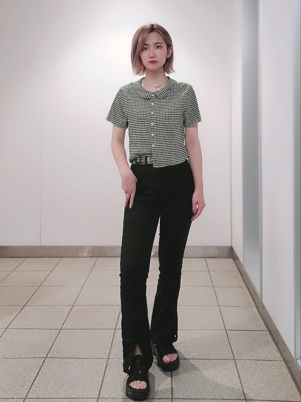 グリーン系のトップス、ブラック系のパンツ、ブラック系のサンダルを着用したレディースの夏コーディネートの3枚目の写真
