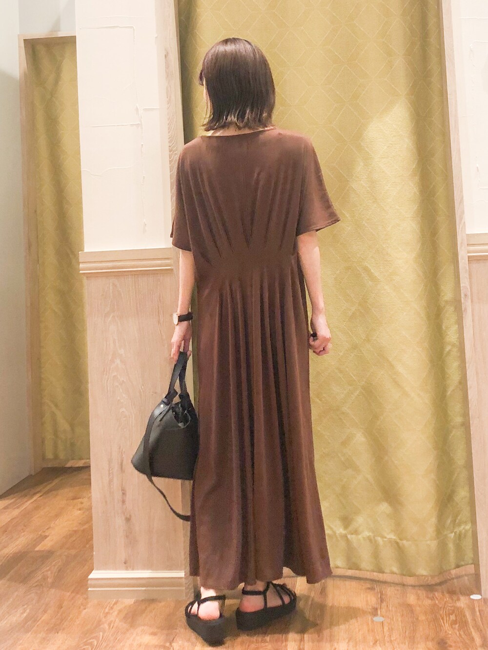 ブラック系のサンダル、ブラック系のトートバッグ、ブラウン系のワンピースを着用したレディースの春コーディネートの2枚目の写真