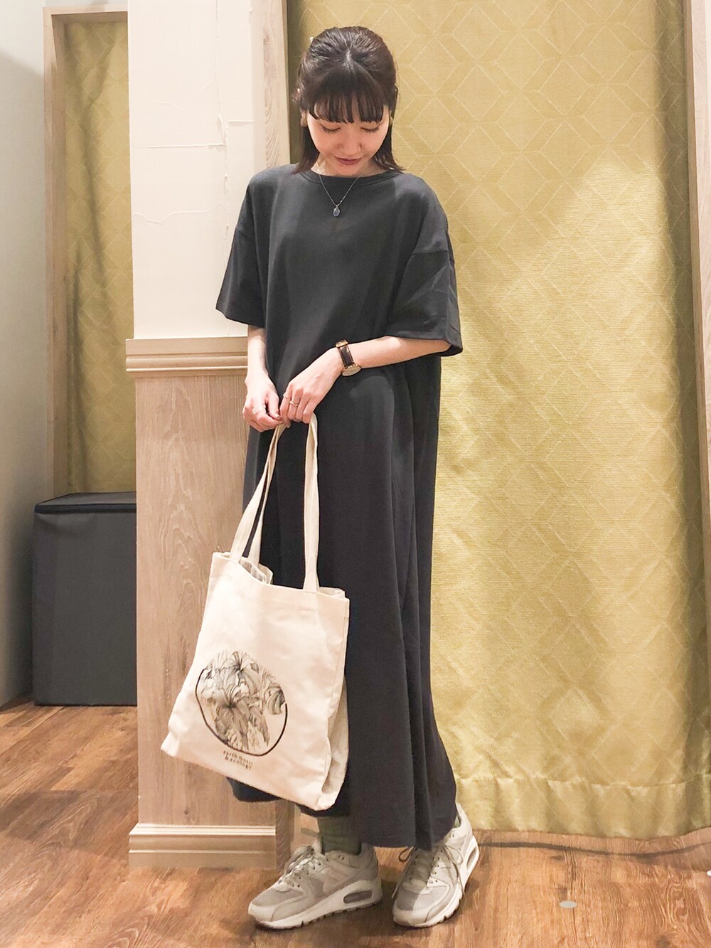 ホワイト系のトートバッグ、グレー系のワンピース、シルバー系のネックレスを着用したレディースの春コーディネートの2枚目の写真