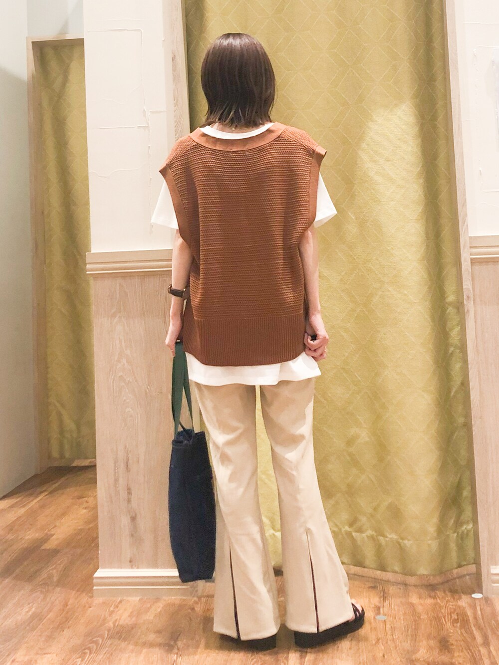 レッド系のニット/セーター、ブルー系のトートバッグ、ベージュ系のその他パンツを着用したレディースの春コーディネートの3枚目の写真