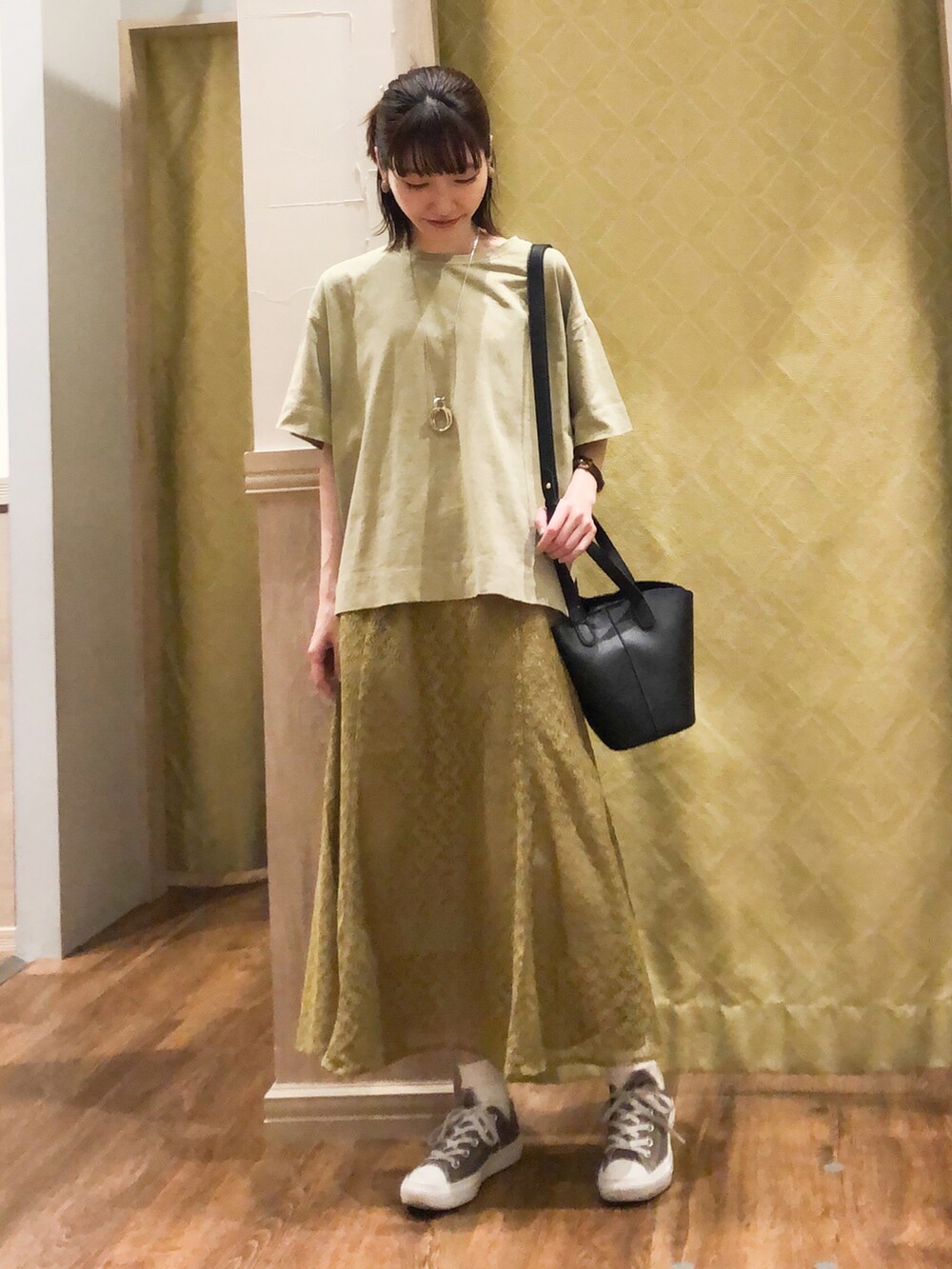 ブラック系のトートバッグ、グリーン系のTシャツ/カットソー、グリーン系のスカートを着用したレディースの春コーディネートの2枚目の写真