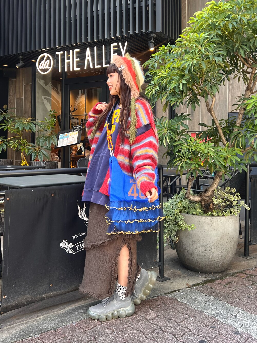 ブラック系のパーカー、レッド系のカーディガン/ボレロ、ブラウン系のスカートを着用したレディースの秋コーディネートの2枚目の写真