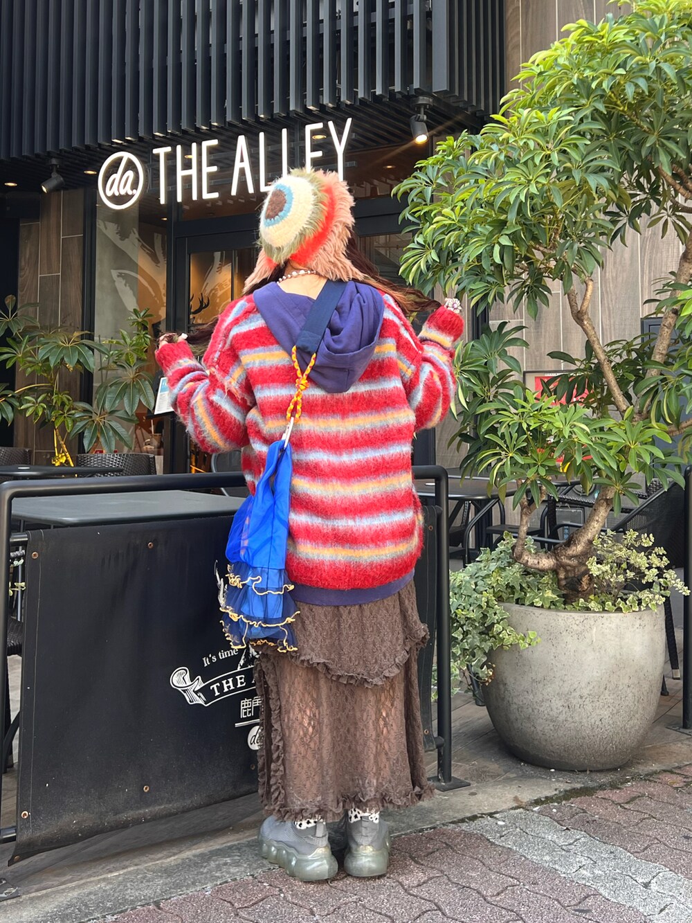 ブラック系のパーカー、レッド系のカーディガン/ボレロ、ブラウン系のスカートを着用したレディースの秋コーディネートの3枚目の写真