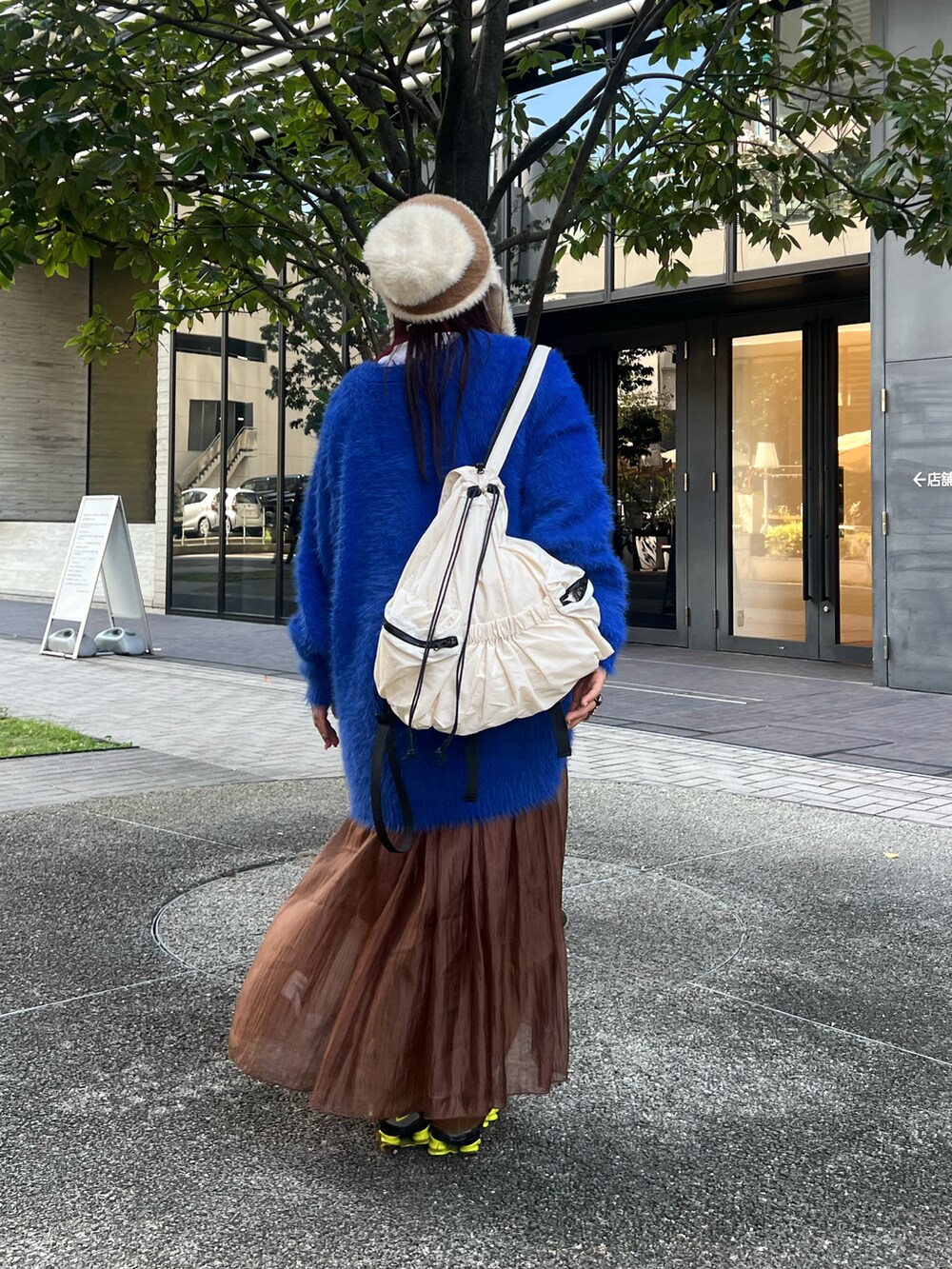 ブルー系のカーディガン/ボレロ、ブラウン系のワンピース、ホワイト系のバックパック/リュックを着用したレディースの秋コーディネートの3枚目の写真