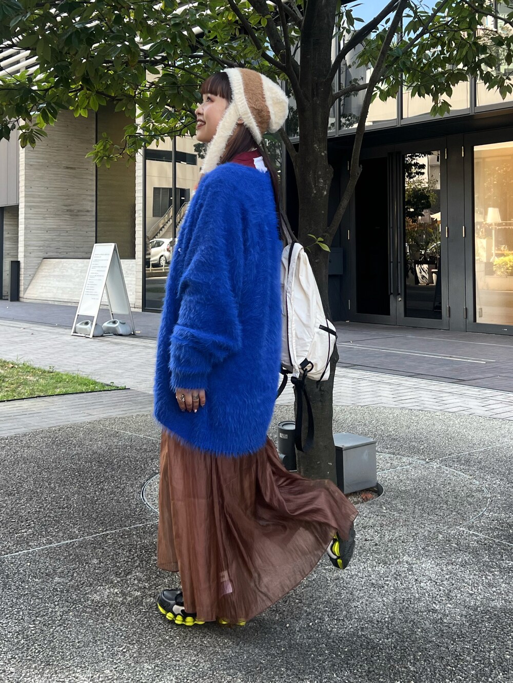 ブルー系のカーディガン/ボレロ、ブラウン系のワンピース、ホワイト系のバックパック/リュックを着用したレディースの秋コーディネートの2枚目の写真