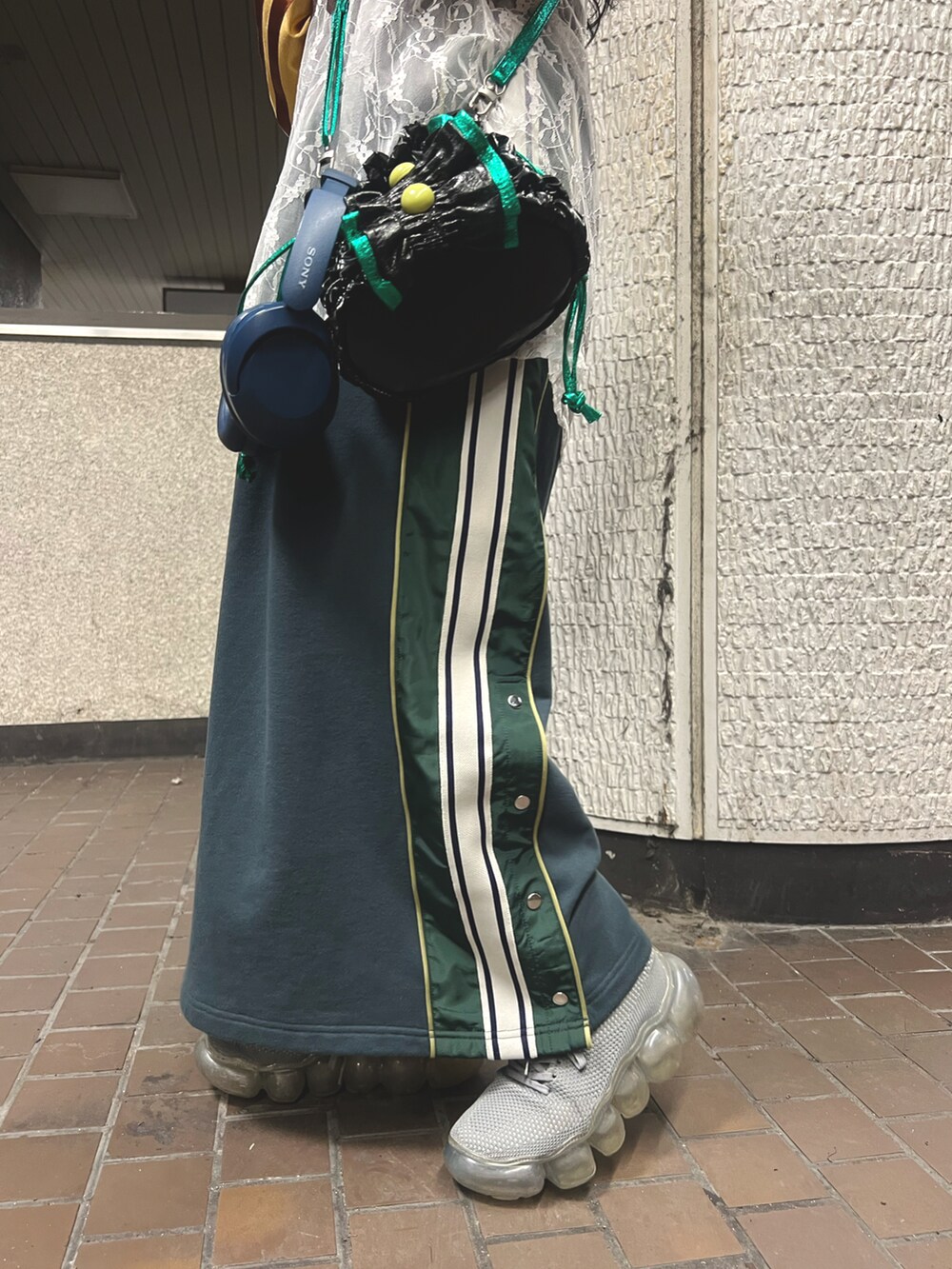 グリーン系のスカート、ブラック系のショルダーバッグ、イエロー系のTシャツ/カットソーを着用したレディースの冬コーディネートの5枚目の写真