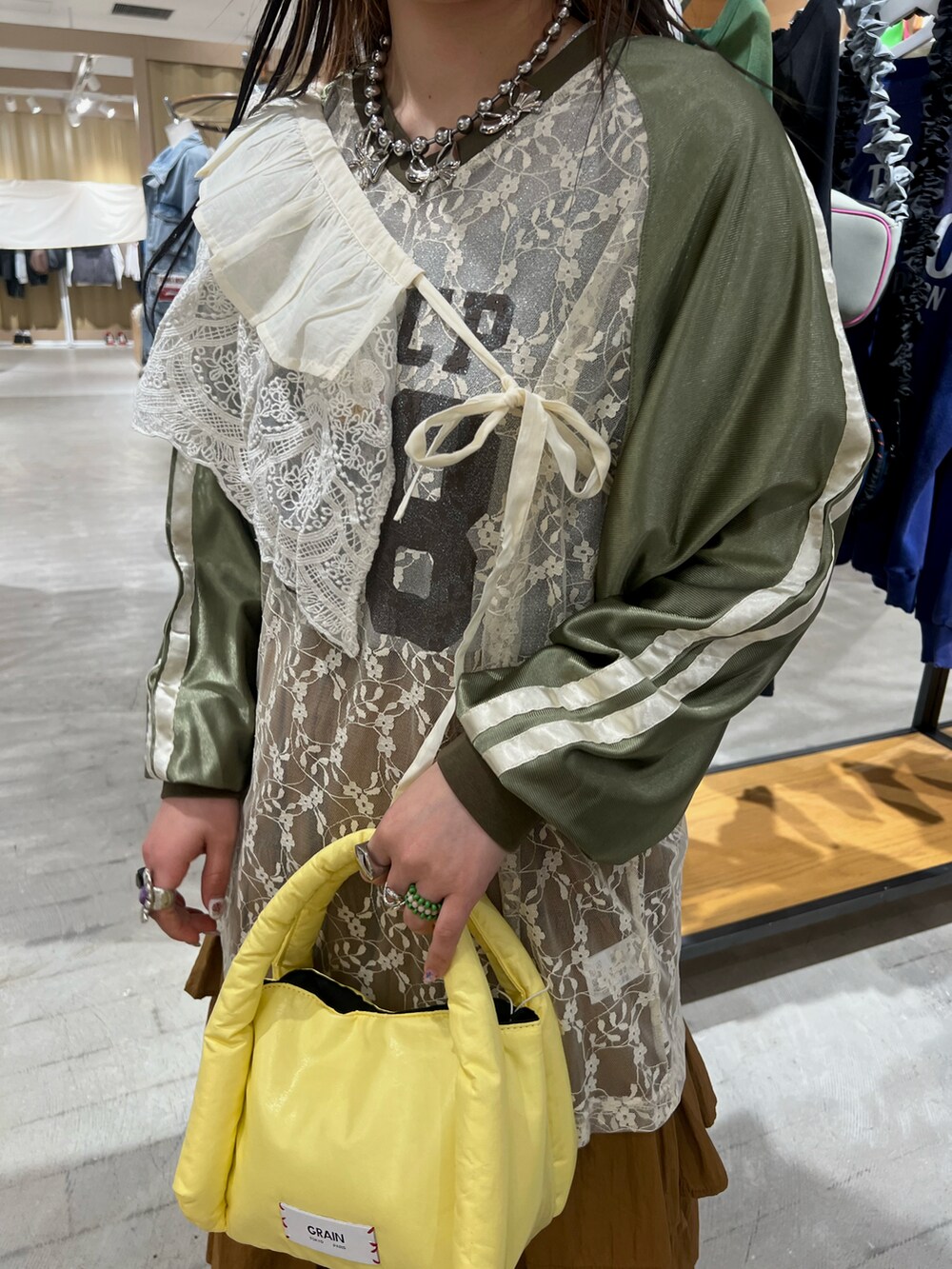 グリーン系のTシャツ/カットソー、イエロー系のスカート、イエロー系のハンドバッグを着用したレディースの春コーディネートの3枚目の写真