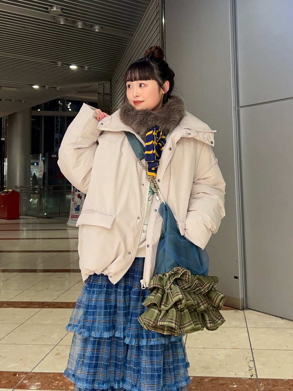 ブラック系のバッグ、グレー系のダウンジャケット/コート、ブルー系のスカートを着用したレディースの冬コーディネートの3枚目の写真