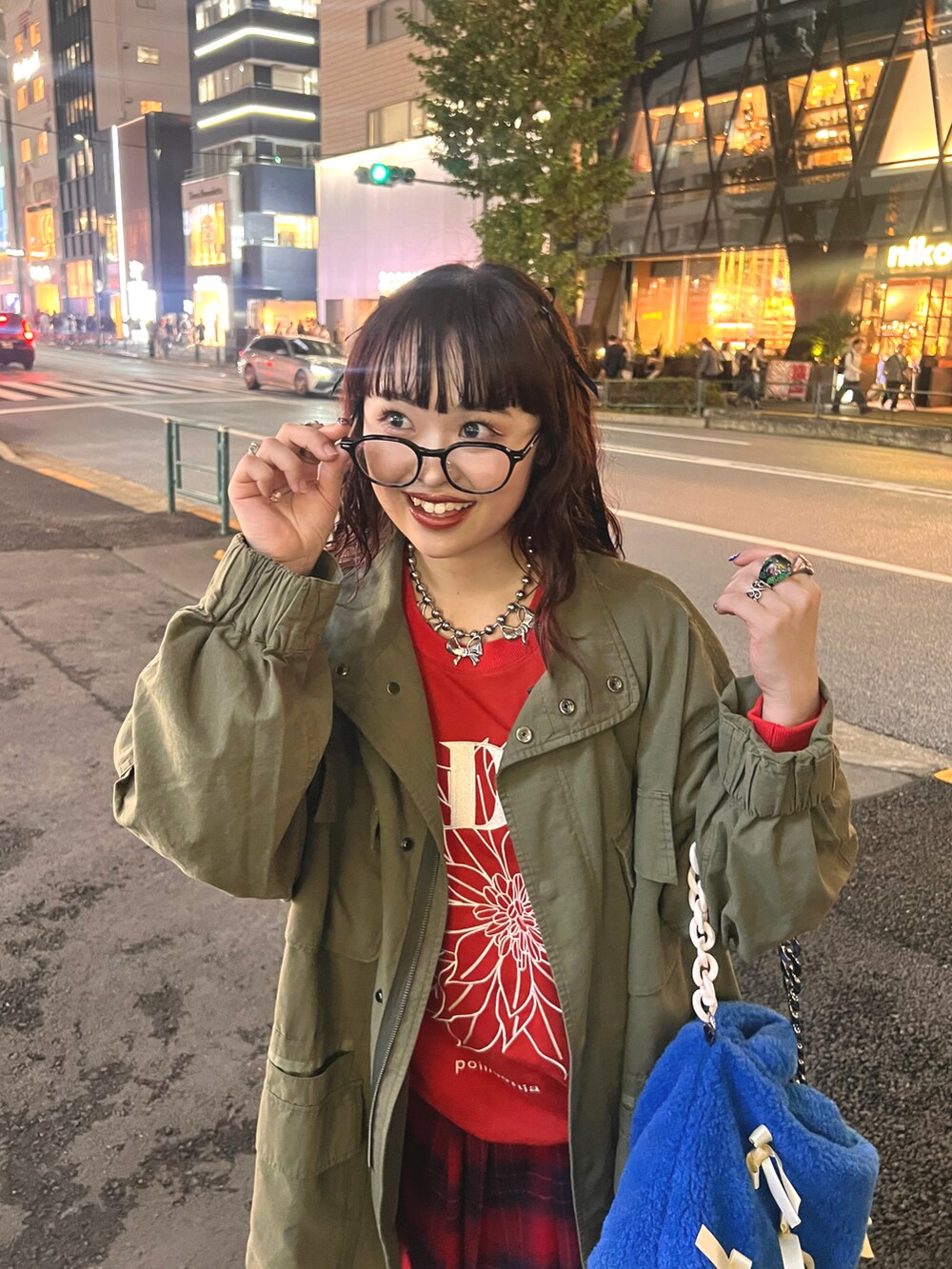 レッド系のスウェット、グリーン系のモッズコート、レッド系のスカートを着用したレディースの秋コーディネートの4枚目の写真