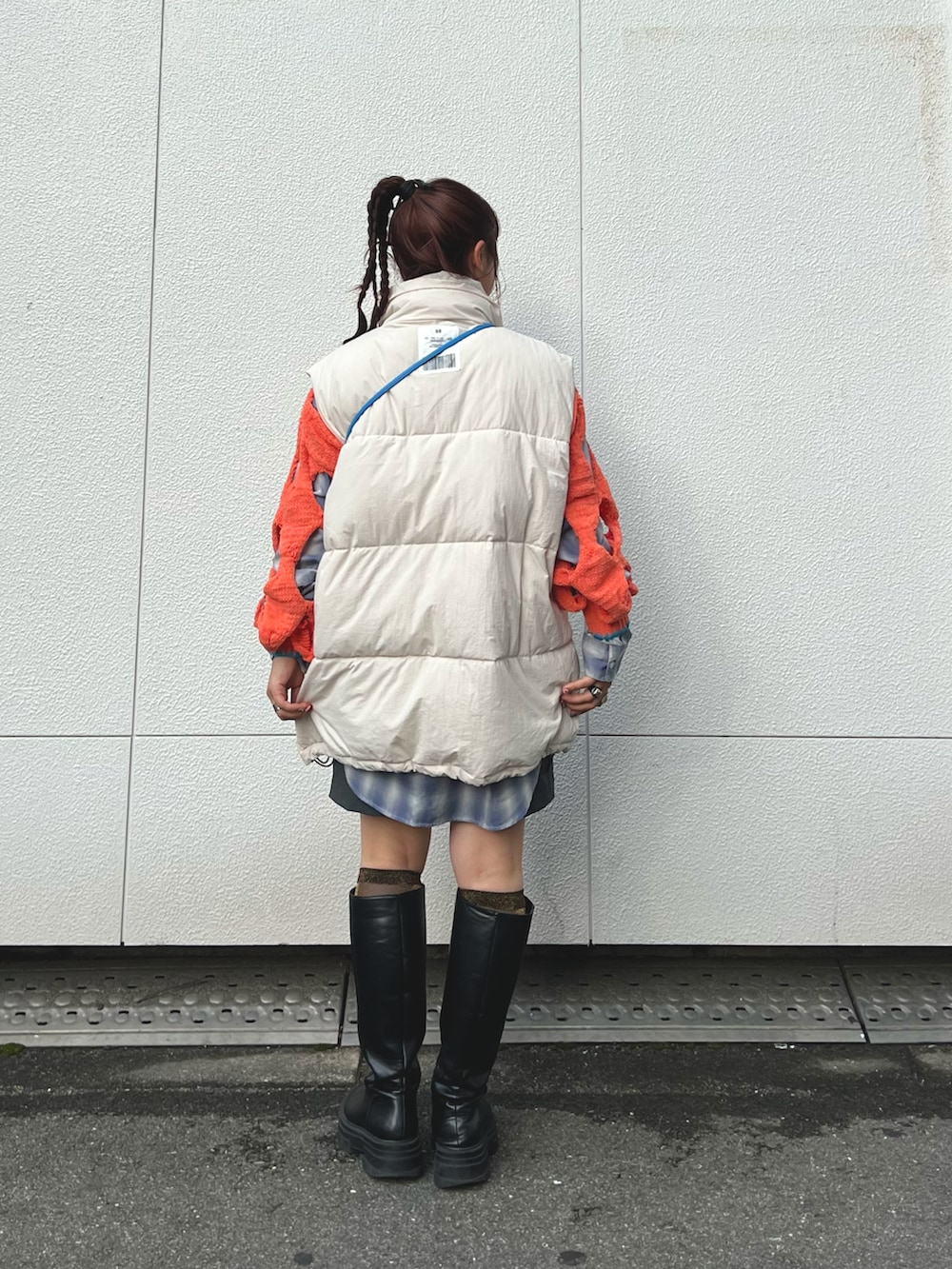 ホワイト系のダウンベスト、オレンジ系のニット/セーター、シルバー系のショルダーバッグを着用したレディースの秋コーディネートの3枚目の写真
